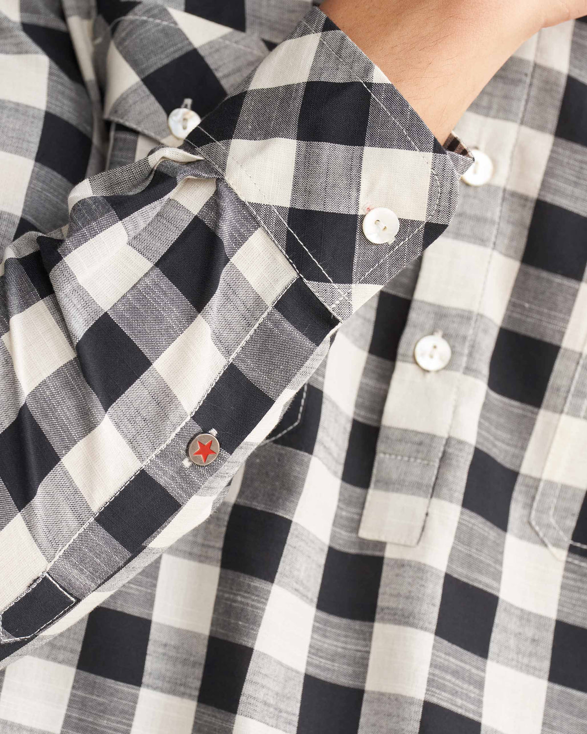 Close-up of a black and ivory checked Nizamuddin kurta cuff with a red star.