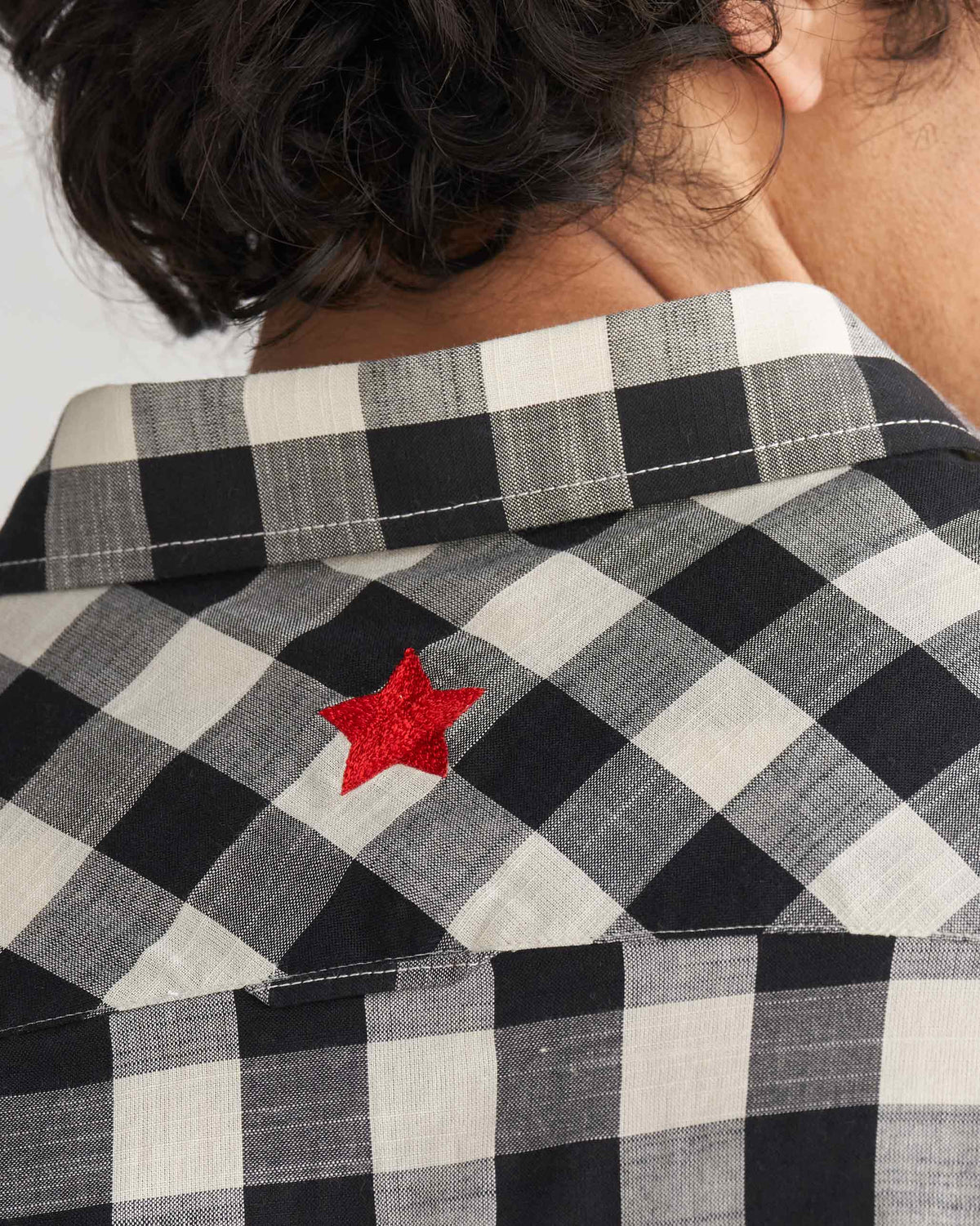 Close-up of the back yoke of a black and ivory checked Nizamuddin kurta with a red star.
