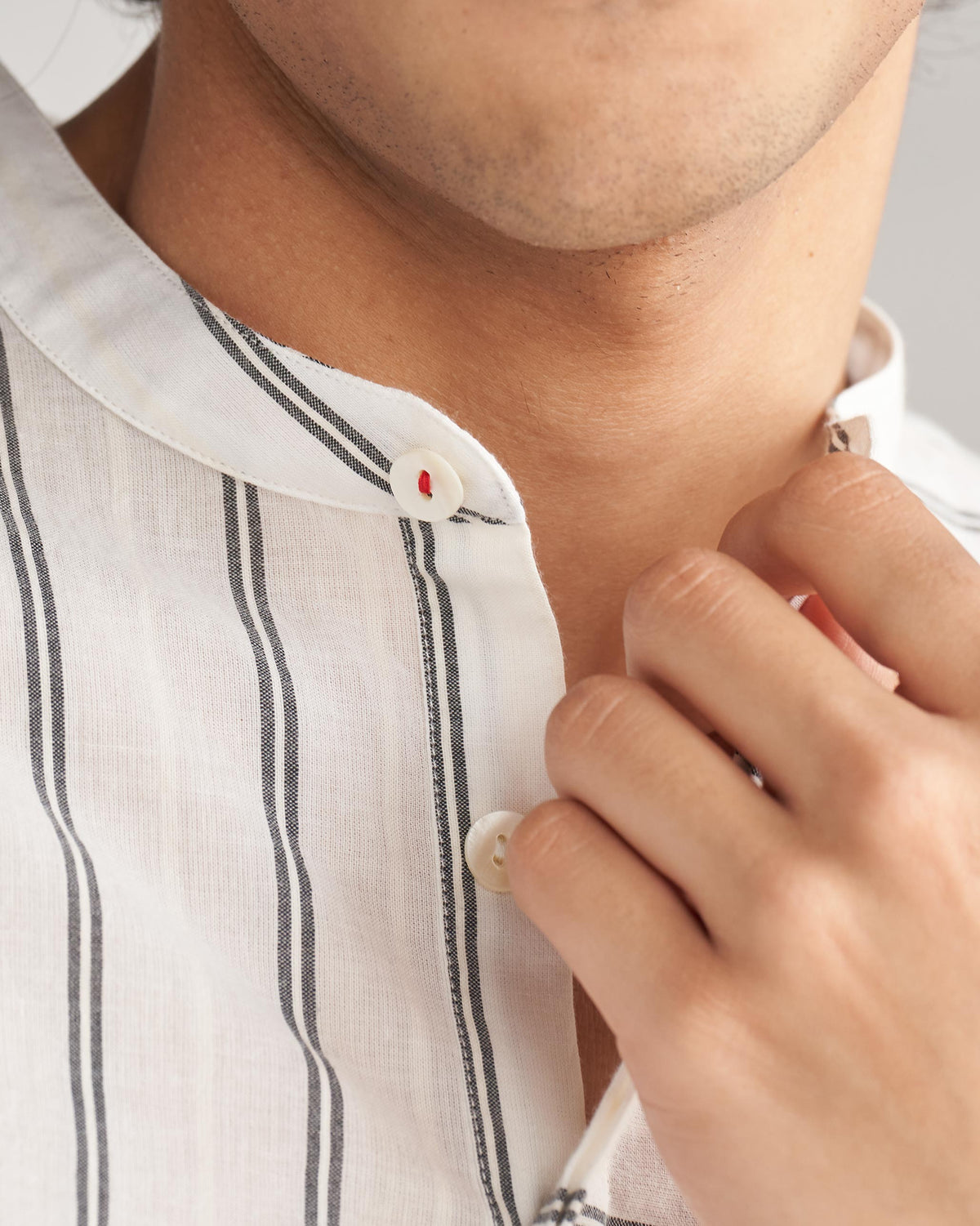 Close-up of an ivory and black Panel Stripe Kurta collar and placket buttons.