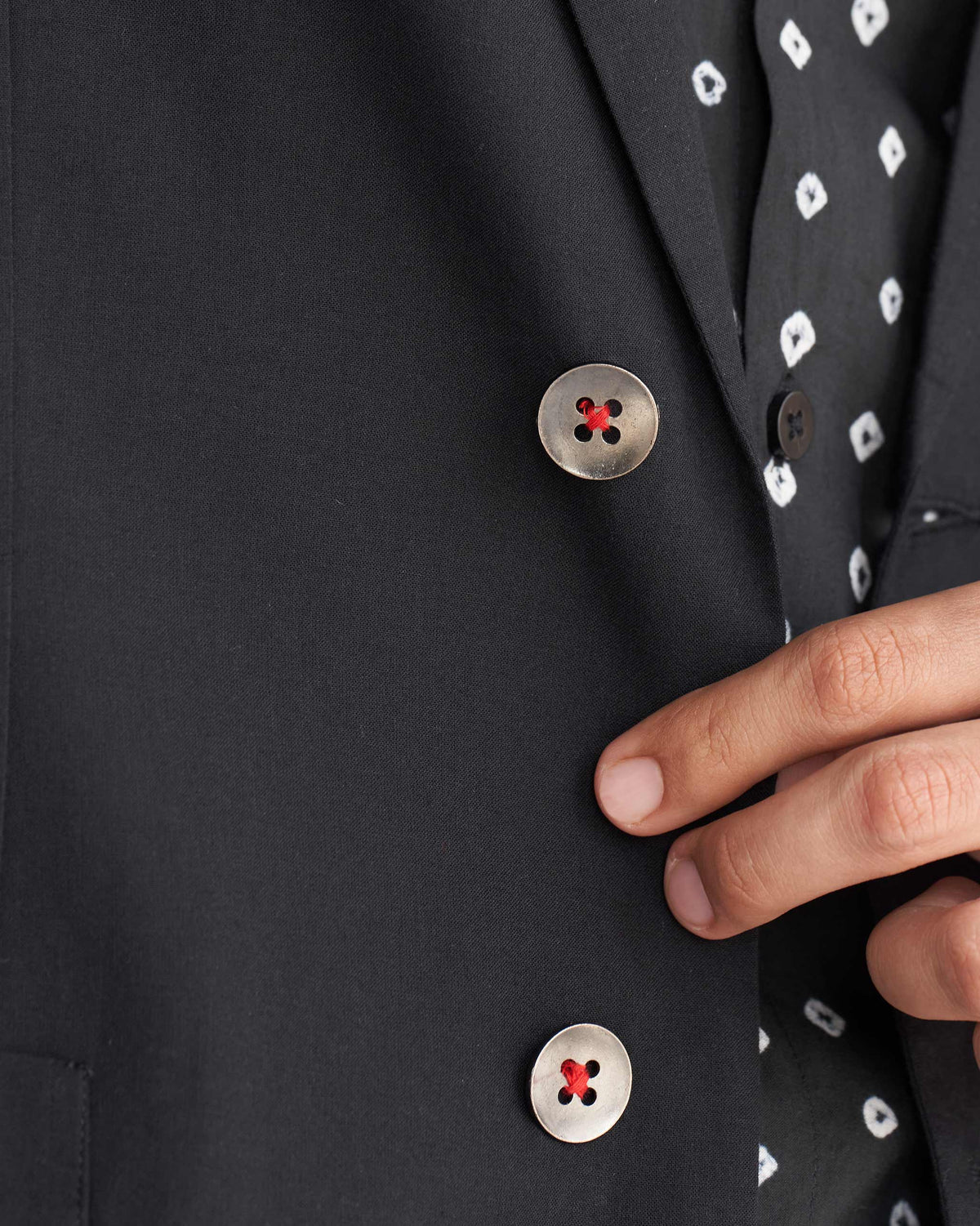 Close-up of a black Midnight Marvel Jacket showing two red-accented front buttons.
