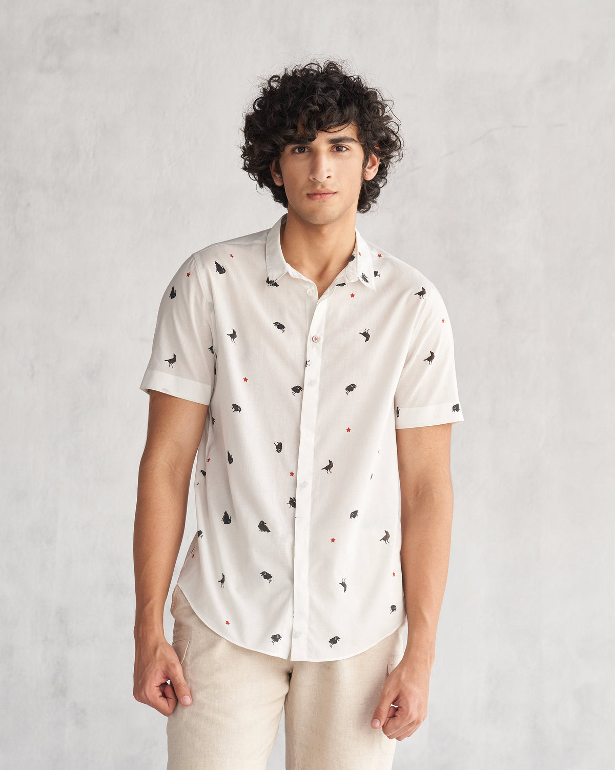 Person wearing the Riverine Shirt in white with small black motifs.