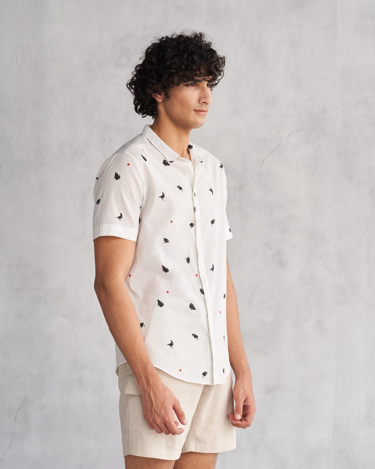Side view of the Riverine Shirt worn by a person, in white with small black motifs.