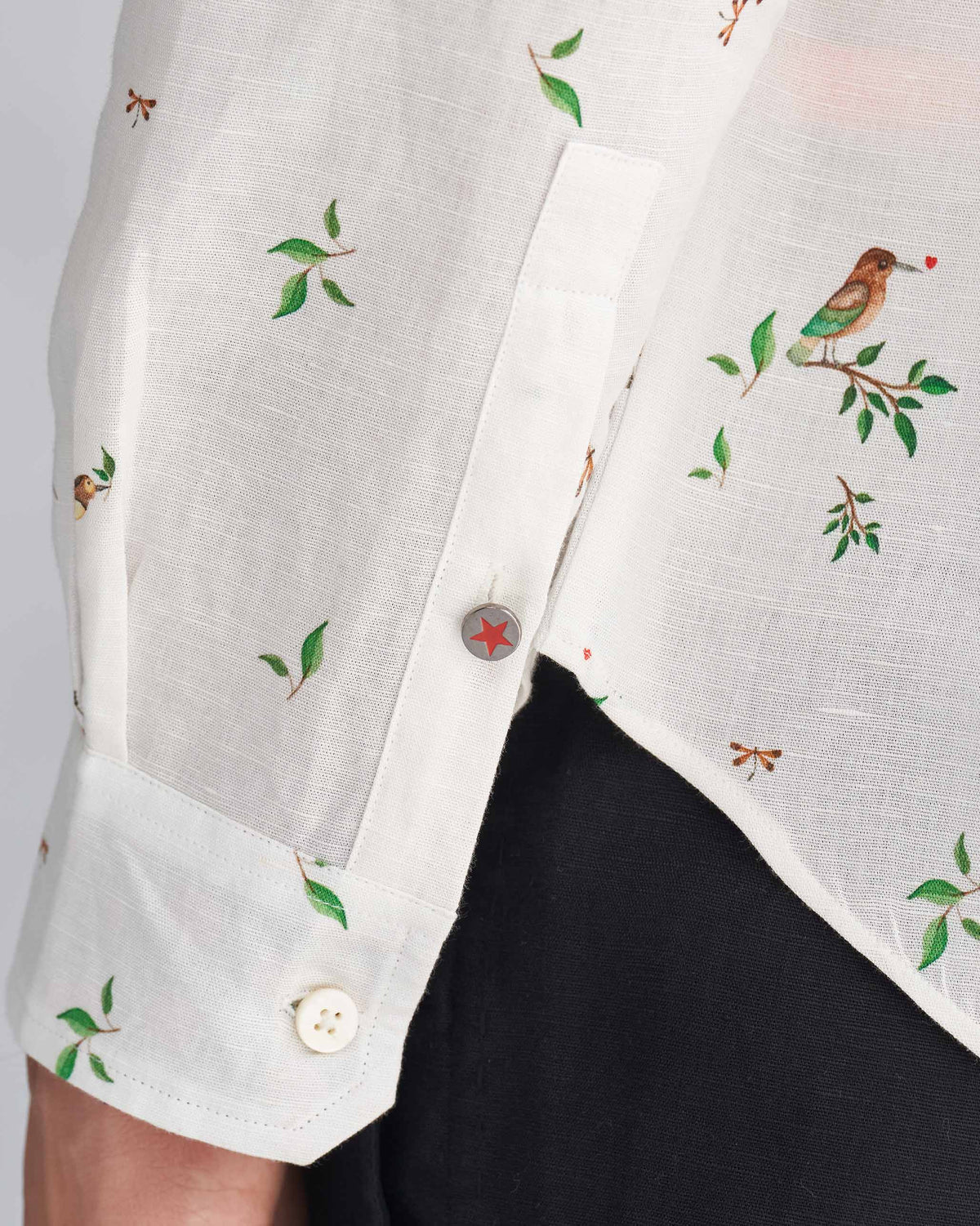 Close-up of a white Nawab Shirt cuff with a red star button.