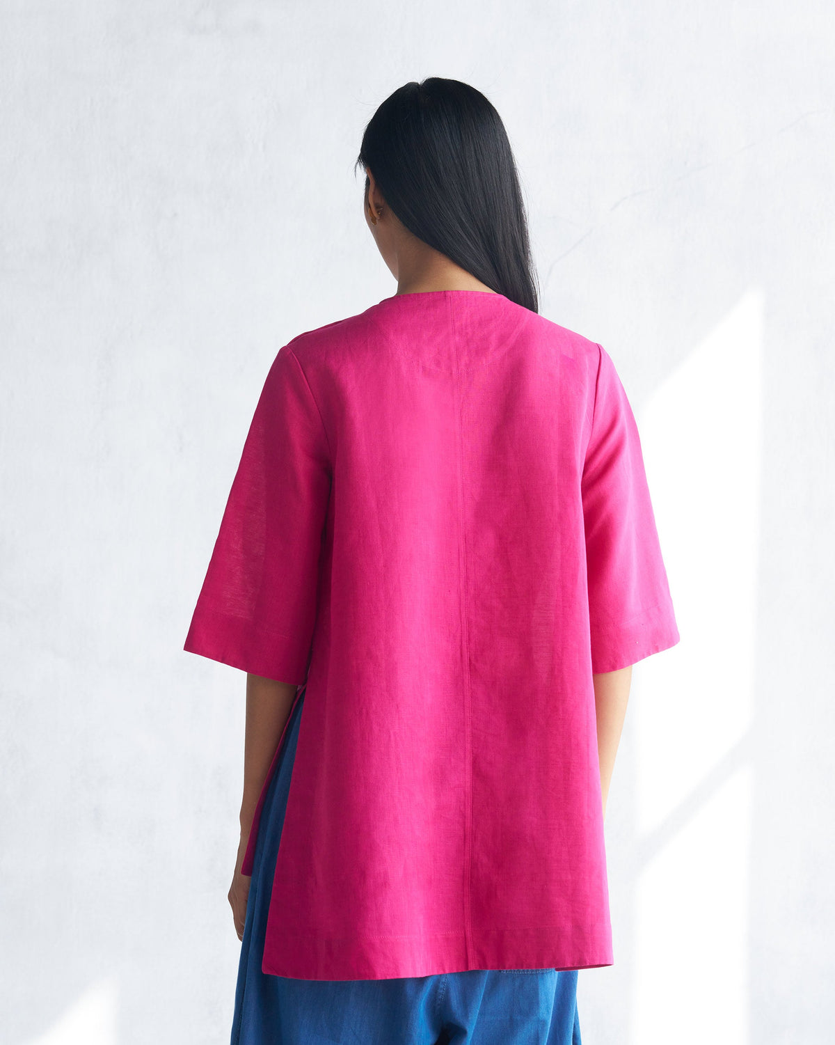 Back of a berry High Slit Top with a center seam and open side slits.