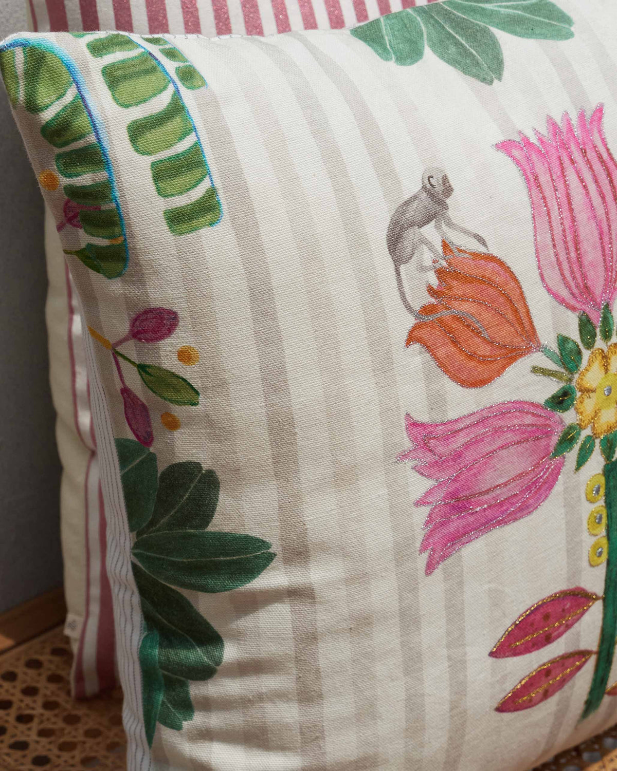 Close-up of Bahari cushion cover showing pink and orange flowers and a small lemur.