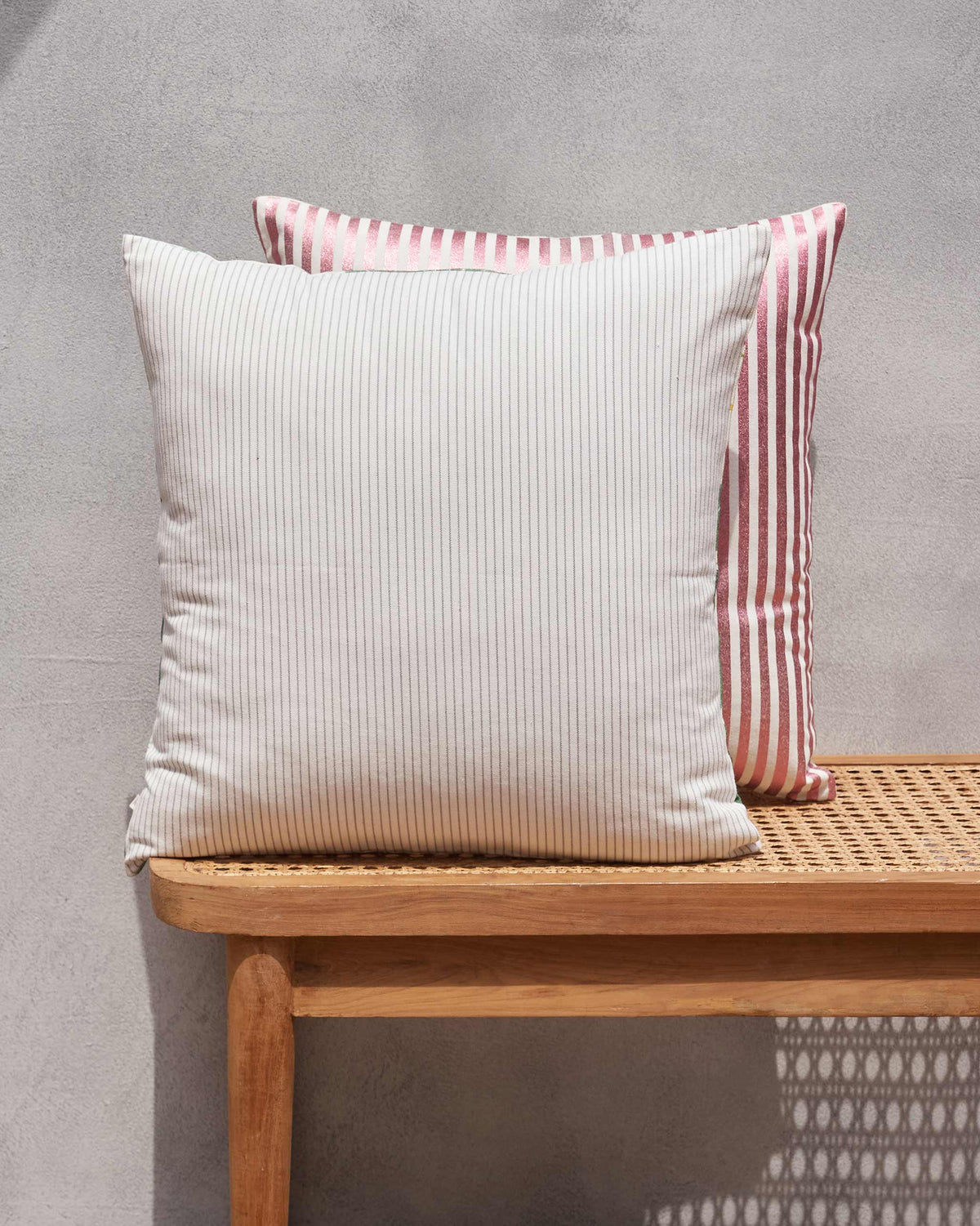Ivory cushion cover in a fine pinstripe on a cane bench.