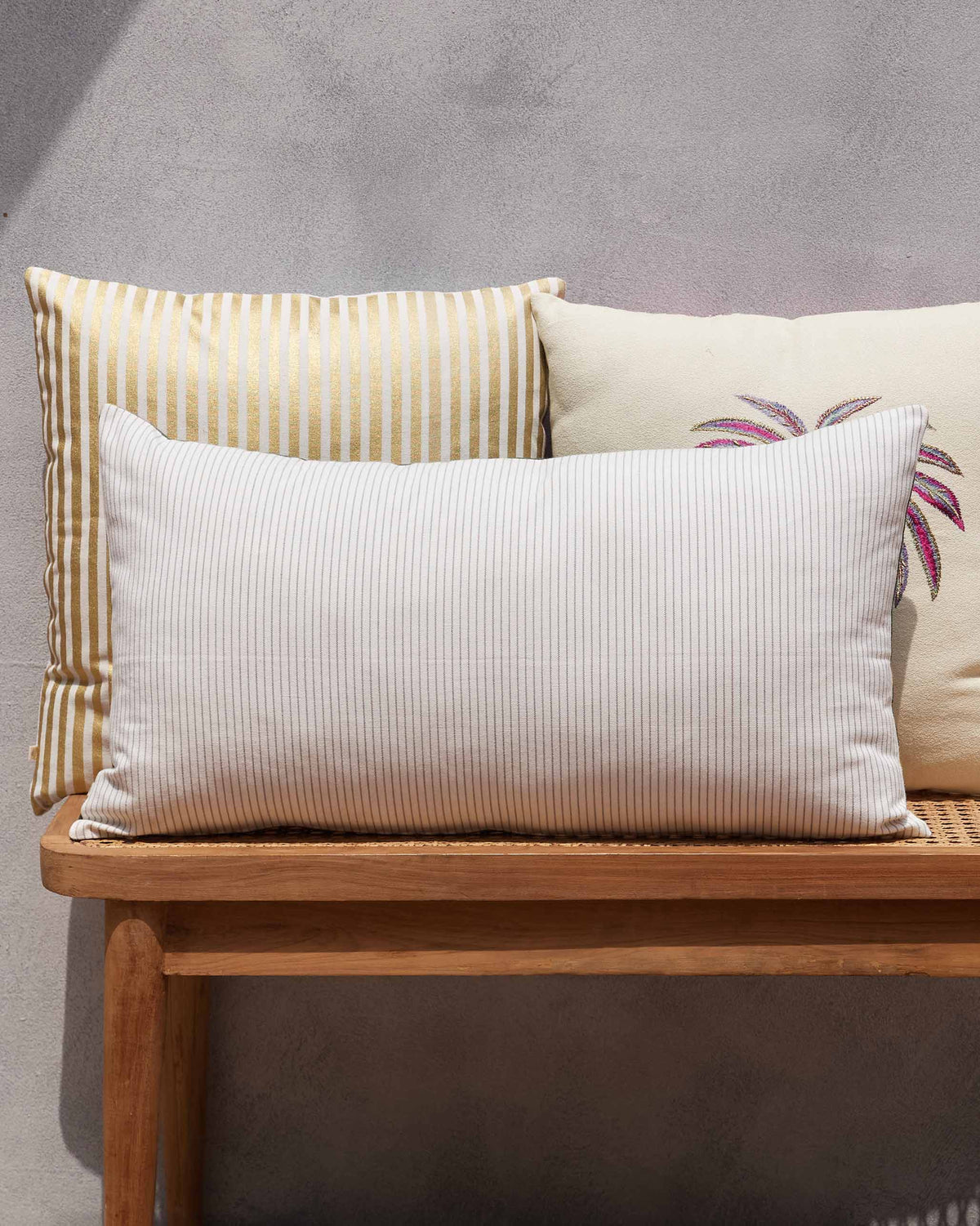 Amani Lumbar Cushion Cover in white pinstriped fabric on a bench.