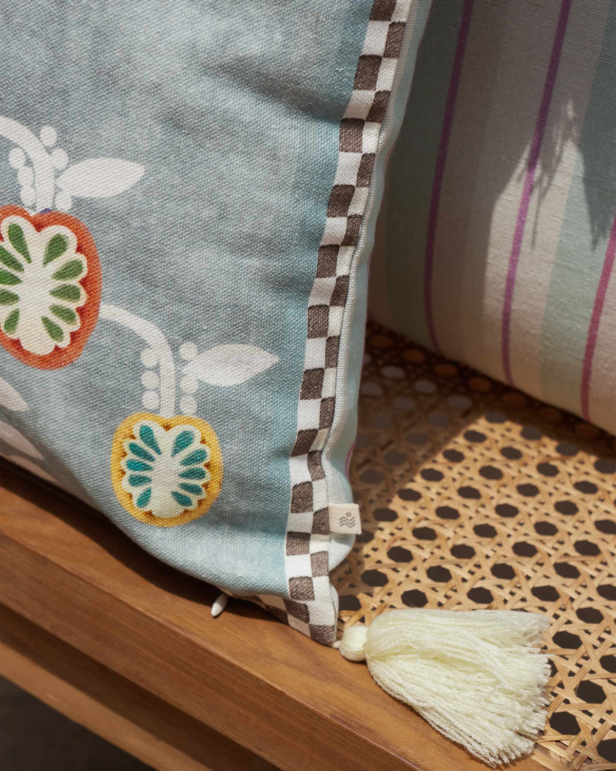 Close-up of Bahari Lumbar Cushion Cover showing its checked edge and fruit motifs.