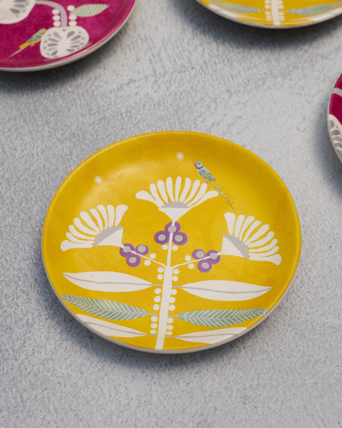 Yellow Bahari tea plate with white flowers and a small bird.