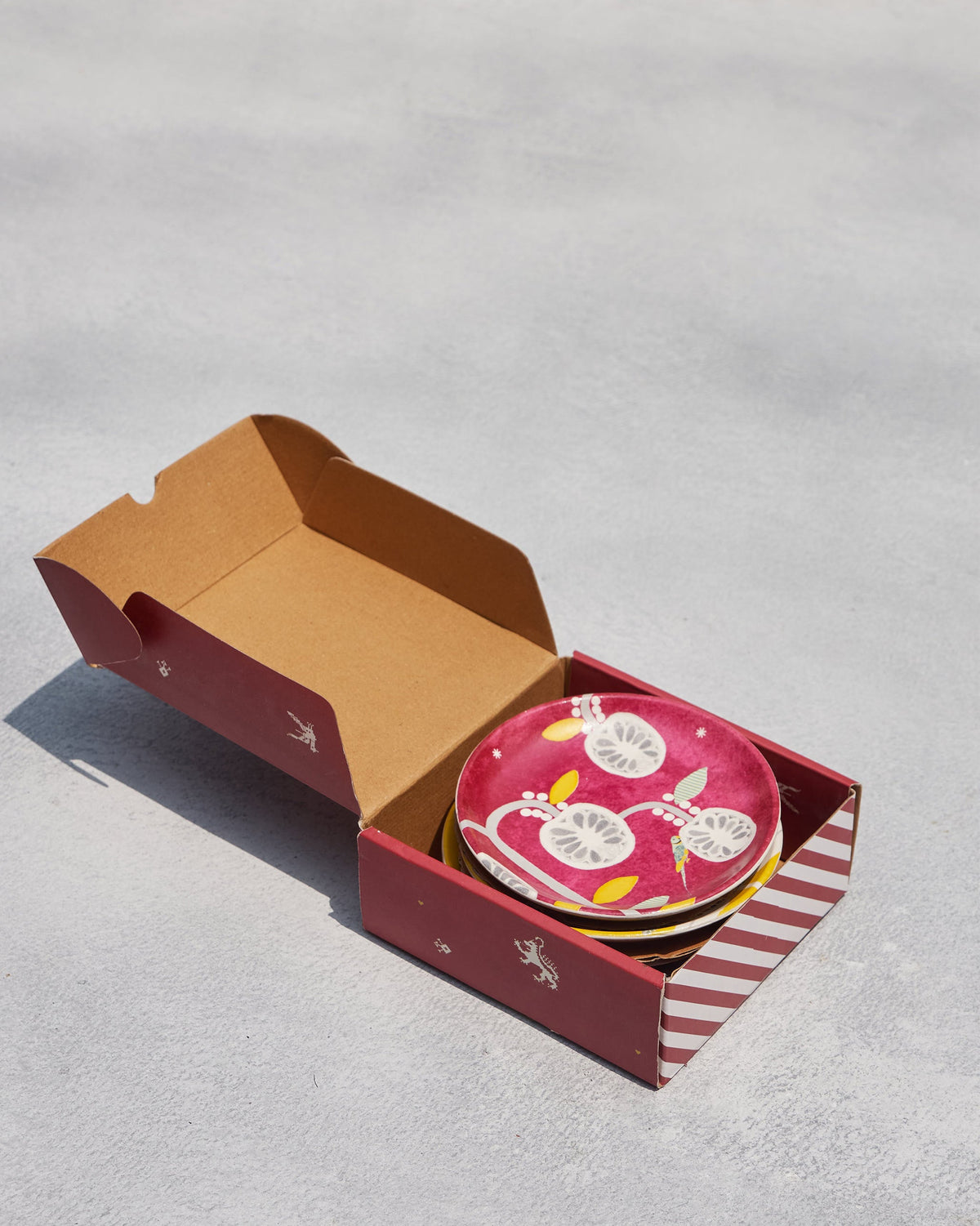 Bahari tea plates stacked in an open gift box.