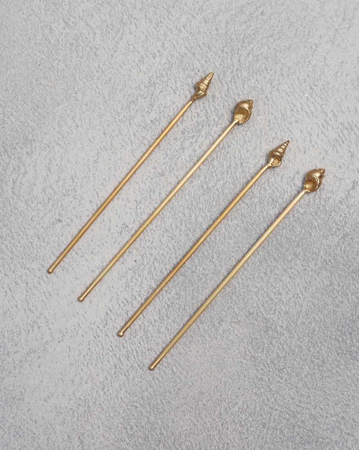 Four Seashells stirrers laid side by side, each with a shell-shaped end.