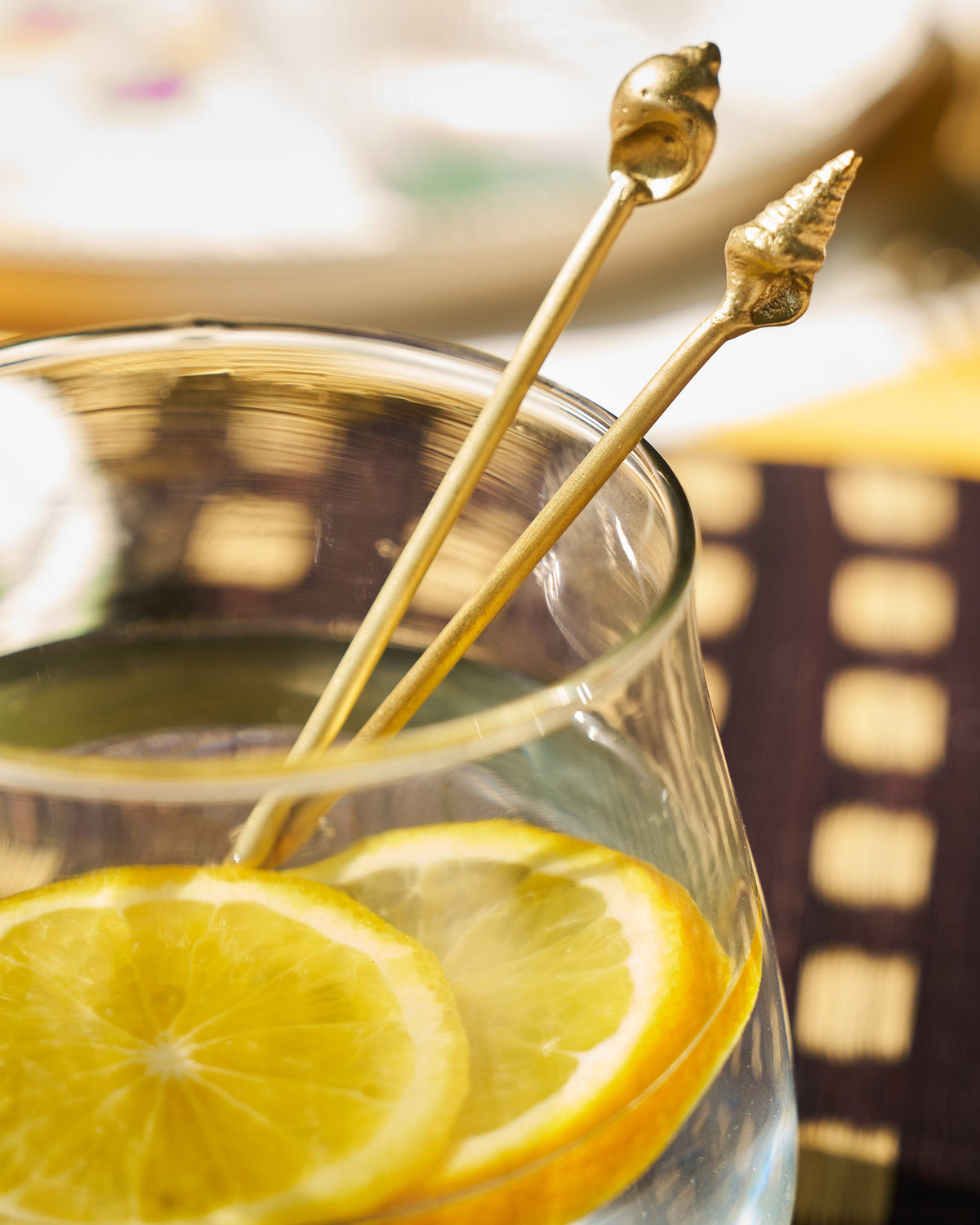 Seashells stirrers in a glass with a lemon slice.