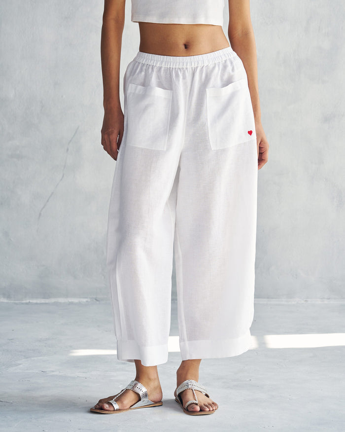 Person wearing white Serene pants with front patch pockets and a red heart detail.