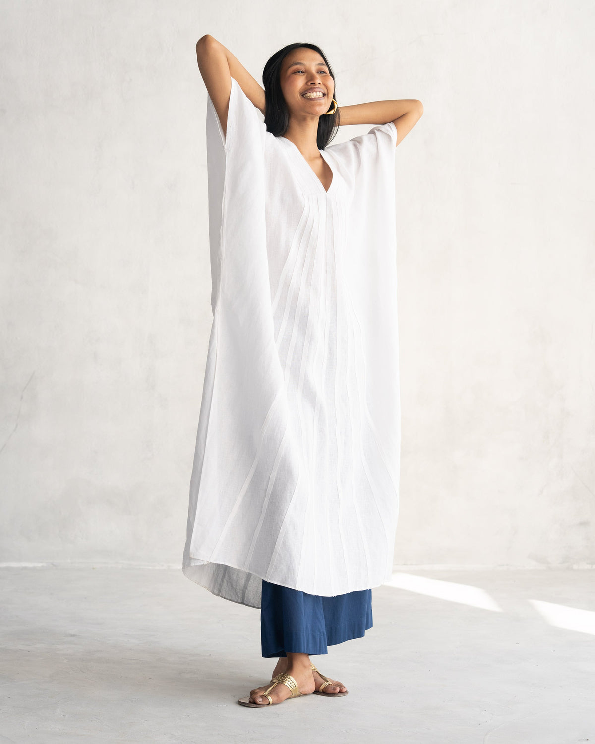 Person wearing a white Tulum kaftan with wide short sleeves.