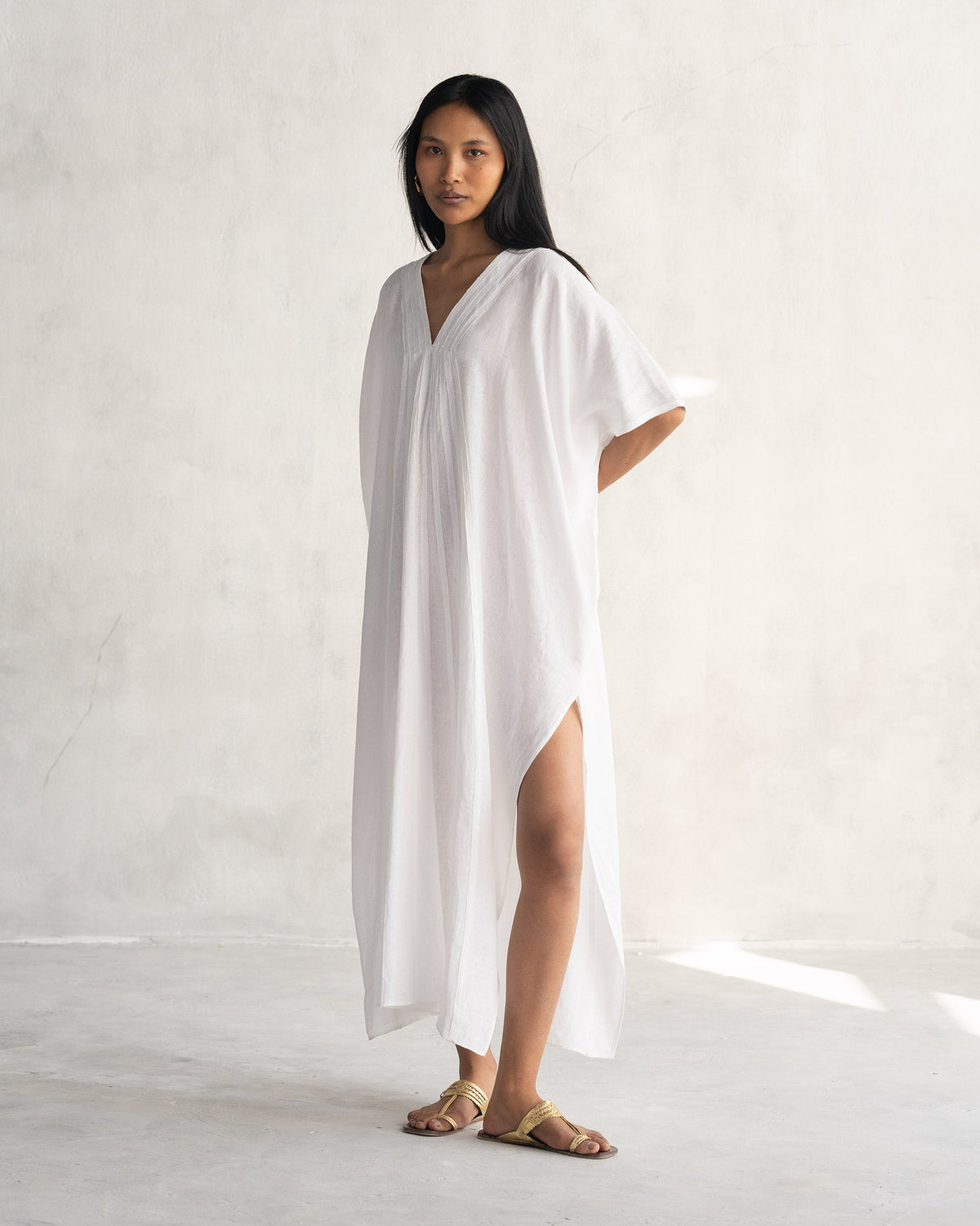Side view of a white Tulum kaftan showing a high side slit.