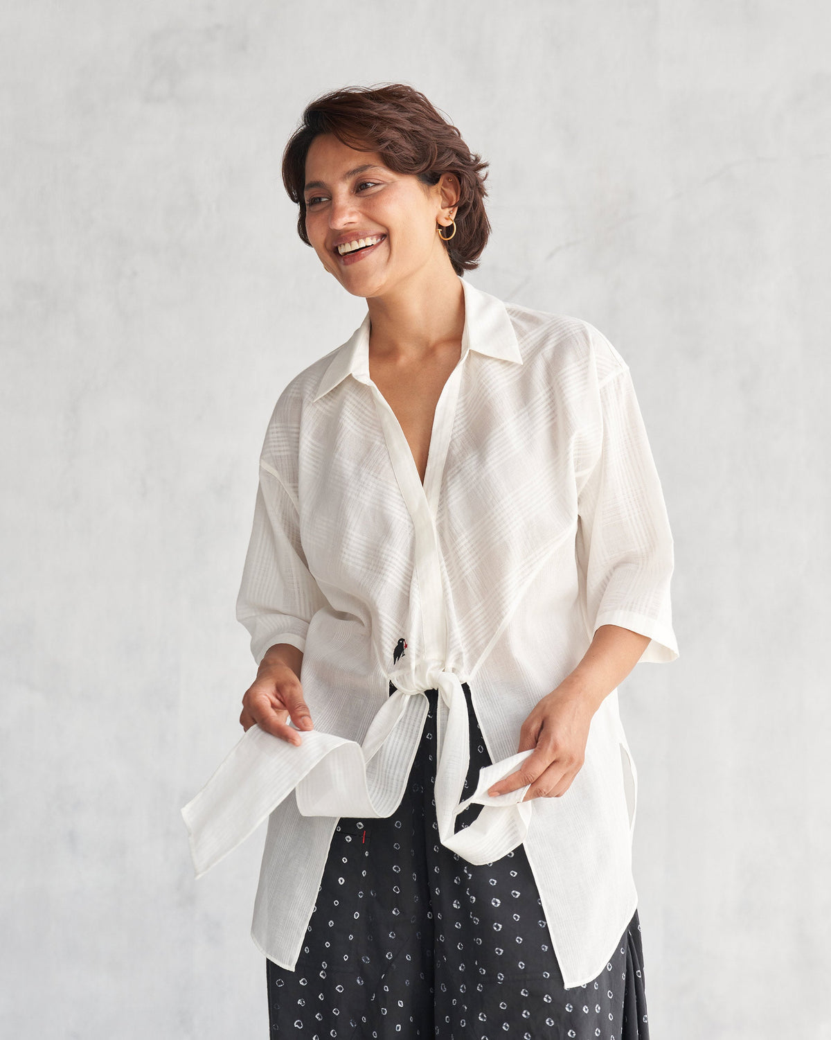 Person wearing an ivory Naomi shirt tied at the waist.