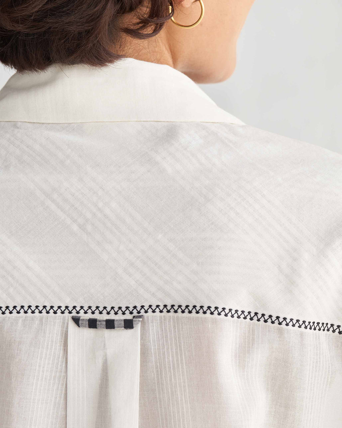 Close-up of the back yoke of an ivory Naomi shirt with black zigzag stitching.