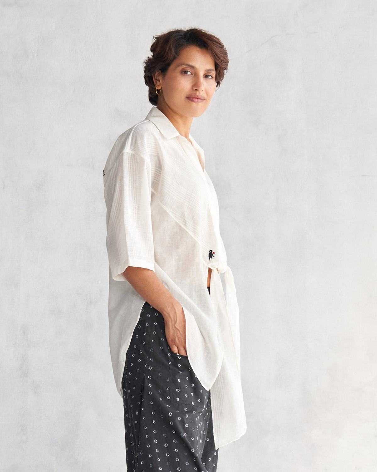 Side view of an ivory Naomi shirt worn by a person.