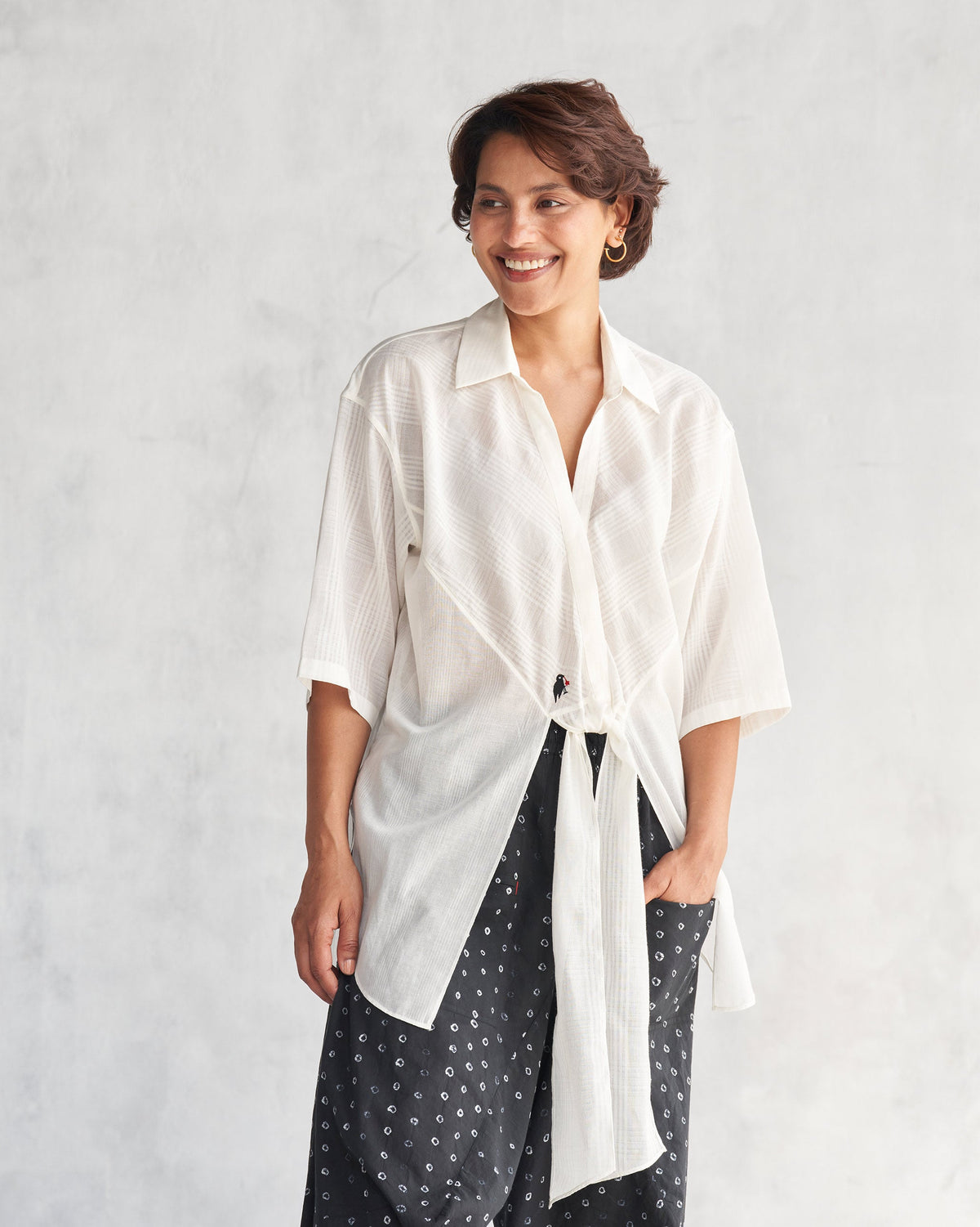Person smiling in an ivory Naomi shirt with a front tie.