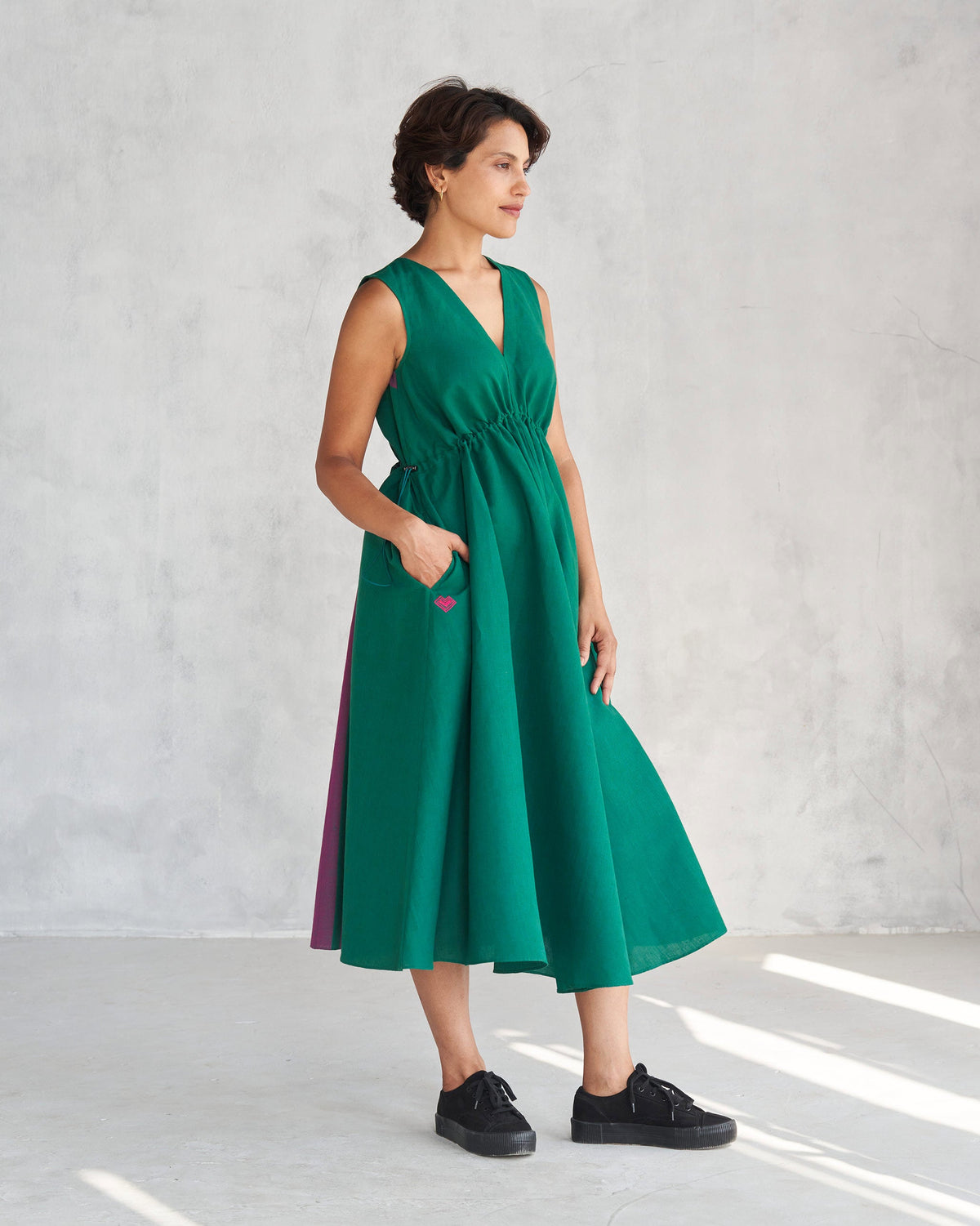Side view of a green Midori dress with a purple panel at the side.