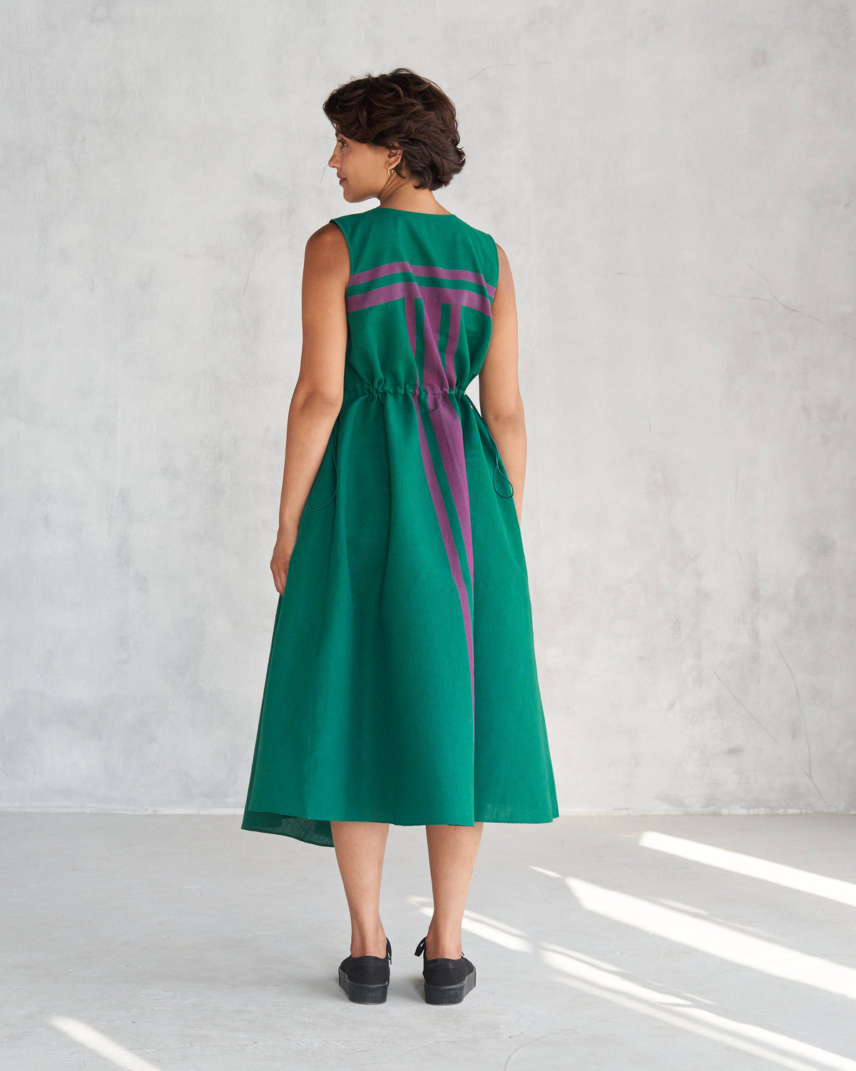 Back of a green Midori dress with purple stripes worn by a person.