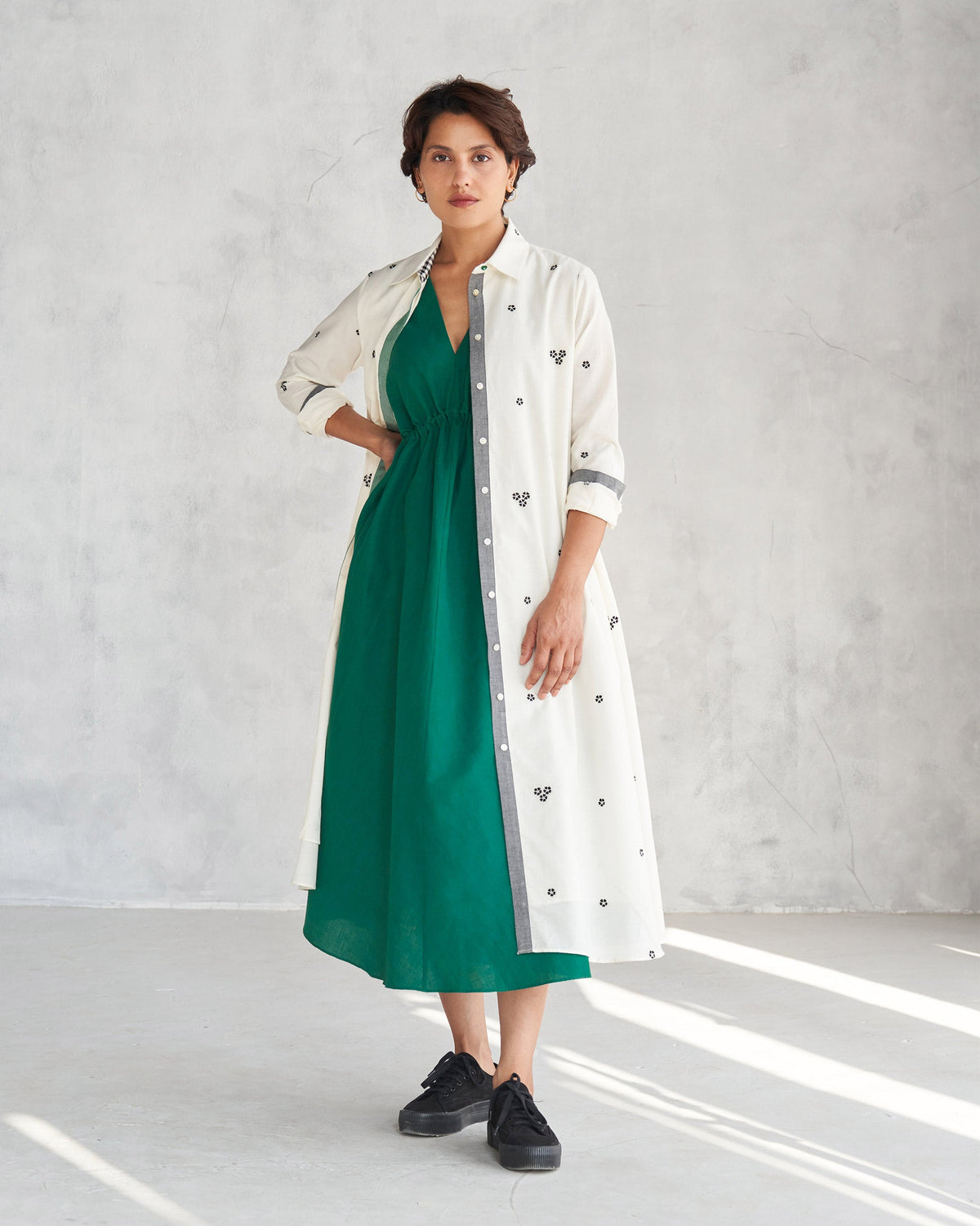 Person wearing a green Midori dress layered under a white jacket.