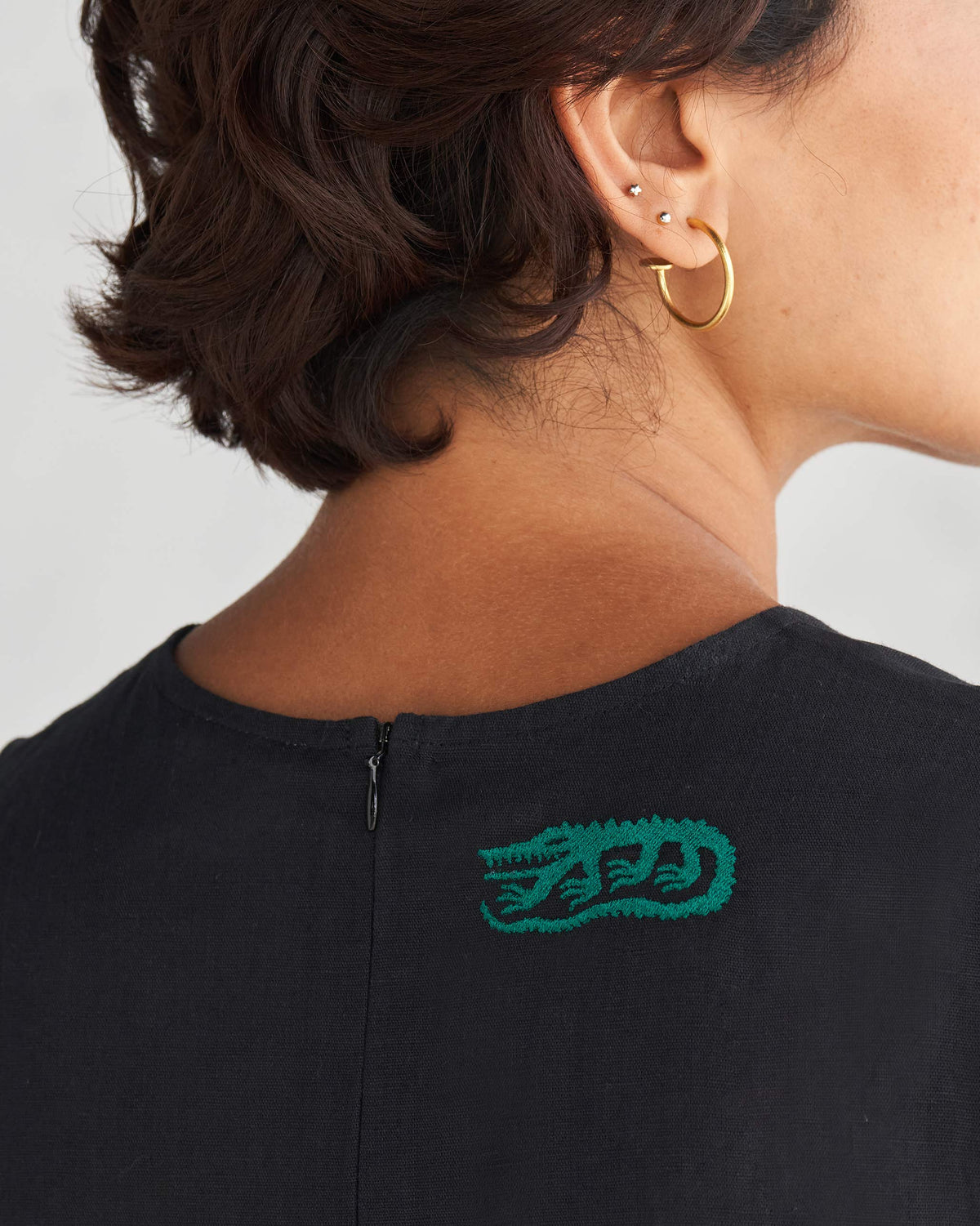 Back of a black Front Knot Jumpsuit with a green embroidered motif at the neck.