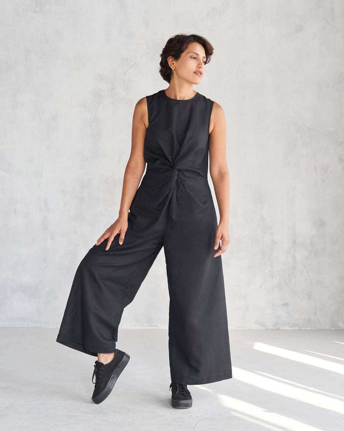 Person wearing a black Front Knot Jumpsuit with a twisted knot and wide legs.