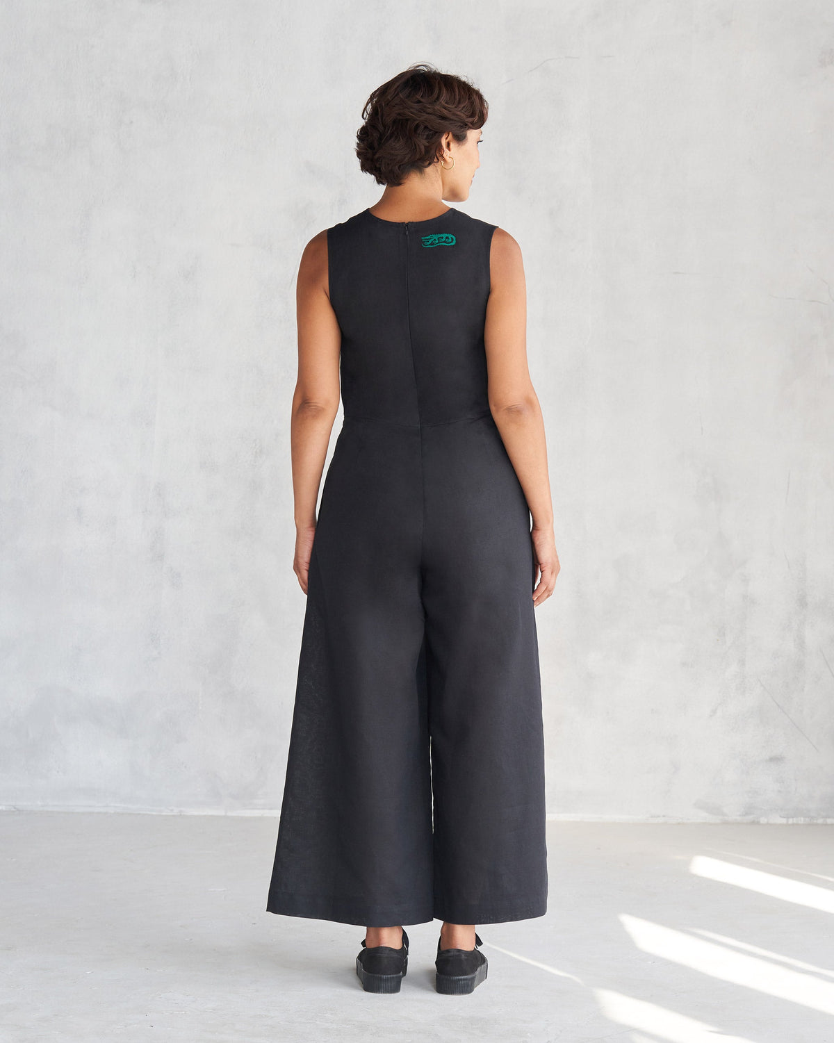 Back of a black Front Knot Jumpsuit with wide legs worn by a person.