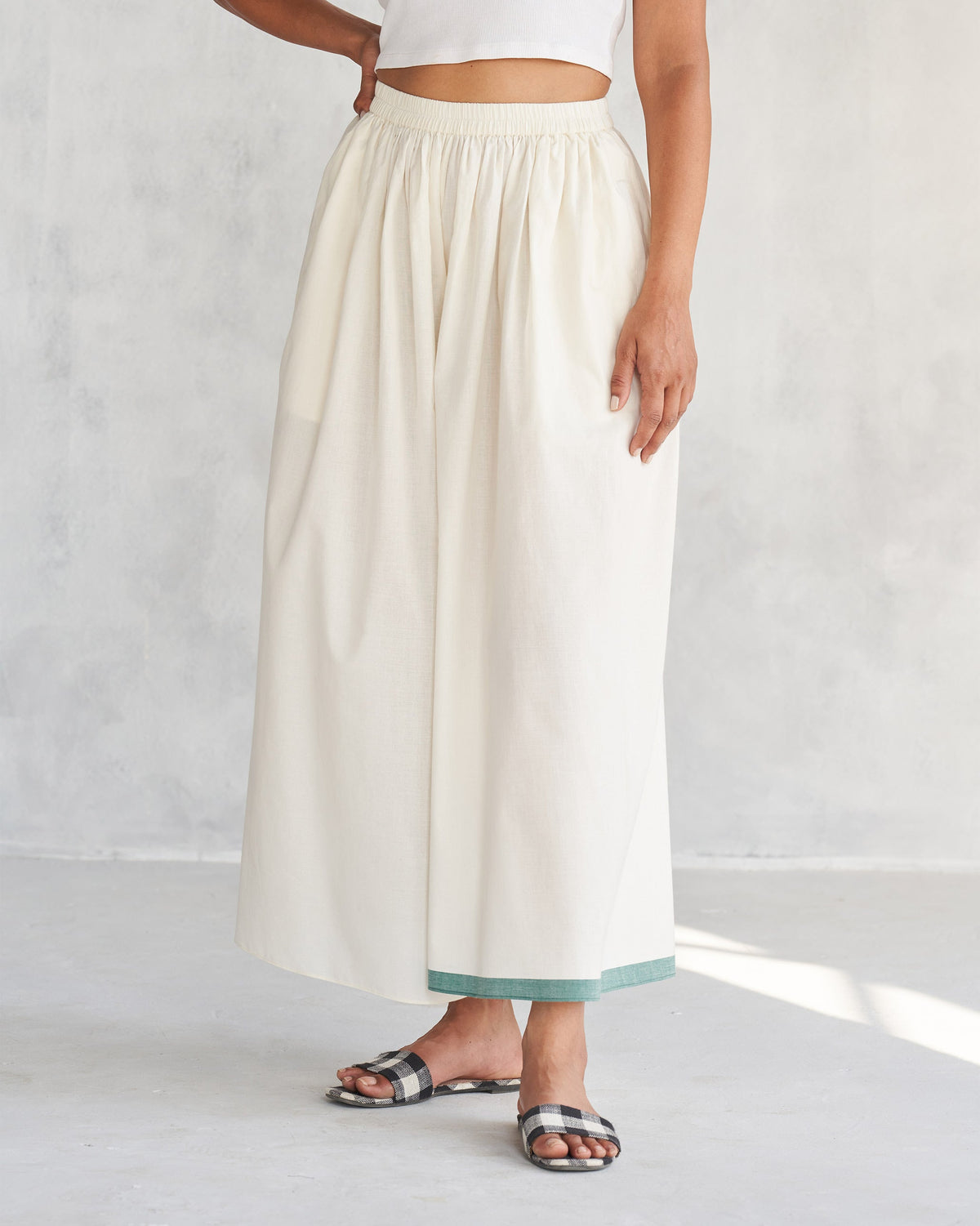 Person wearing ivory Shiro Hem Pants with a teal hem band.