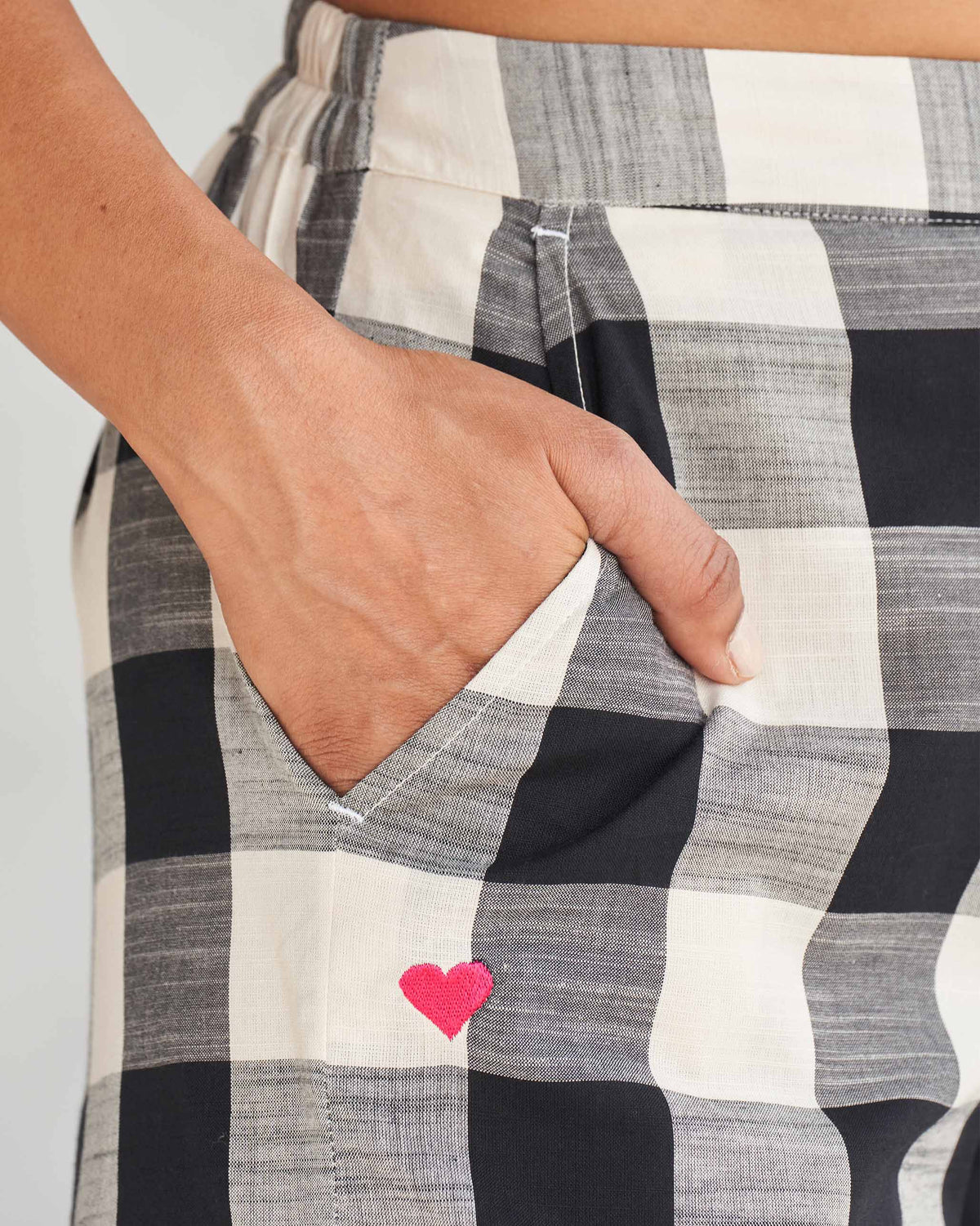 Close-up of black and ivory Midori Pants showing a pink heart embroidery on the pocket.