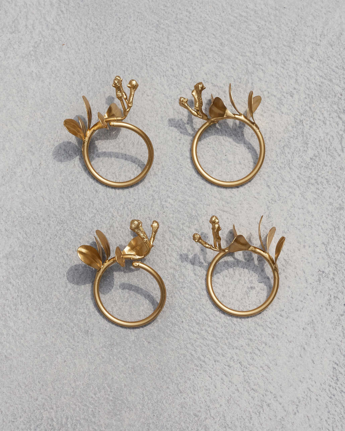 Four gold Clove Napkin Rings with leaves and buds.