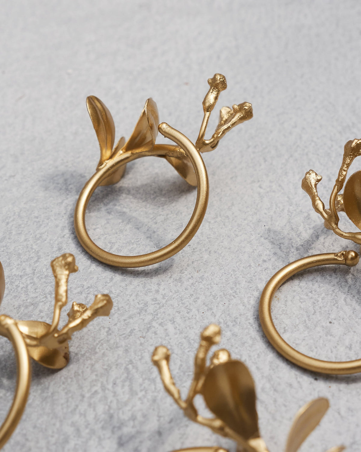 Close-up of a gold Clove Napkin Ring showing its leaves and buds.