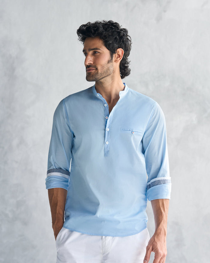 Person wearing a light blue Pondicherry shirt with striped cuff lining.