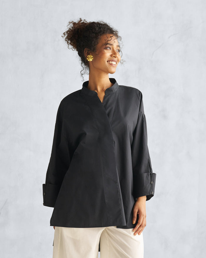 Person wearing a black Cirrus shirt with a deep V neckline and wide cuffs.