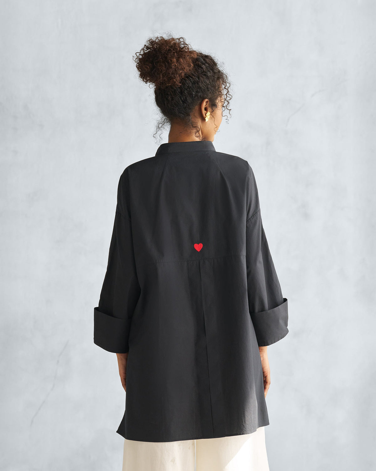 Back of a black Cirrus shirt with red heart embroidery and a box pleat.