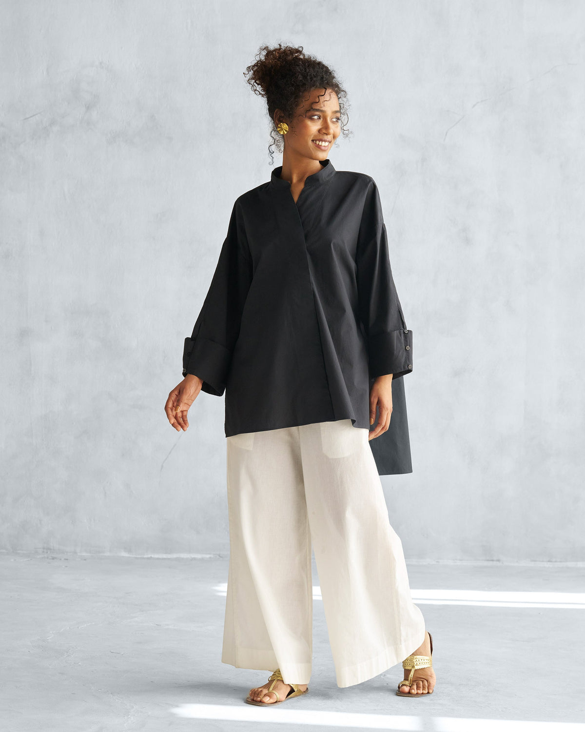 Person wearing a black Cirrus shirt with a high-low hem and wide cuffs.