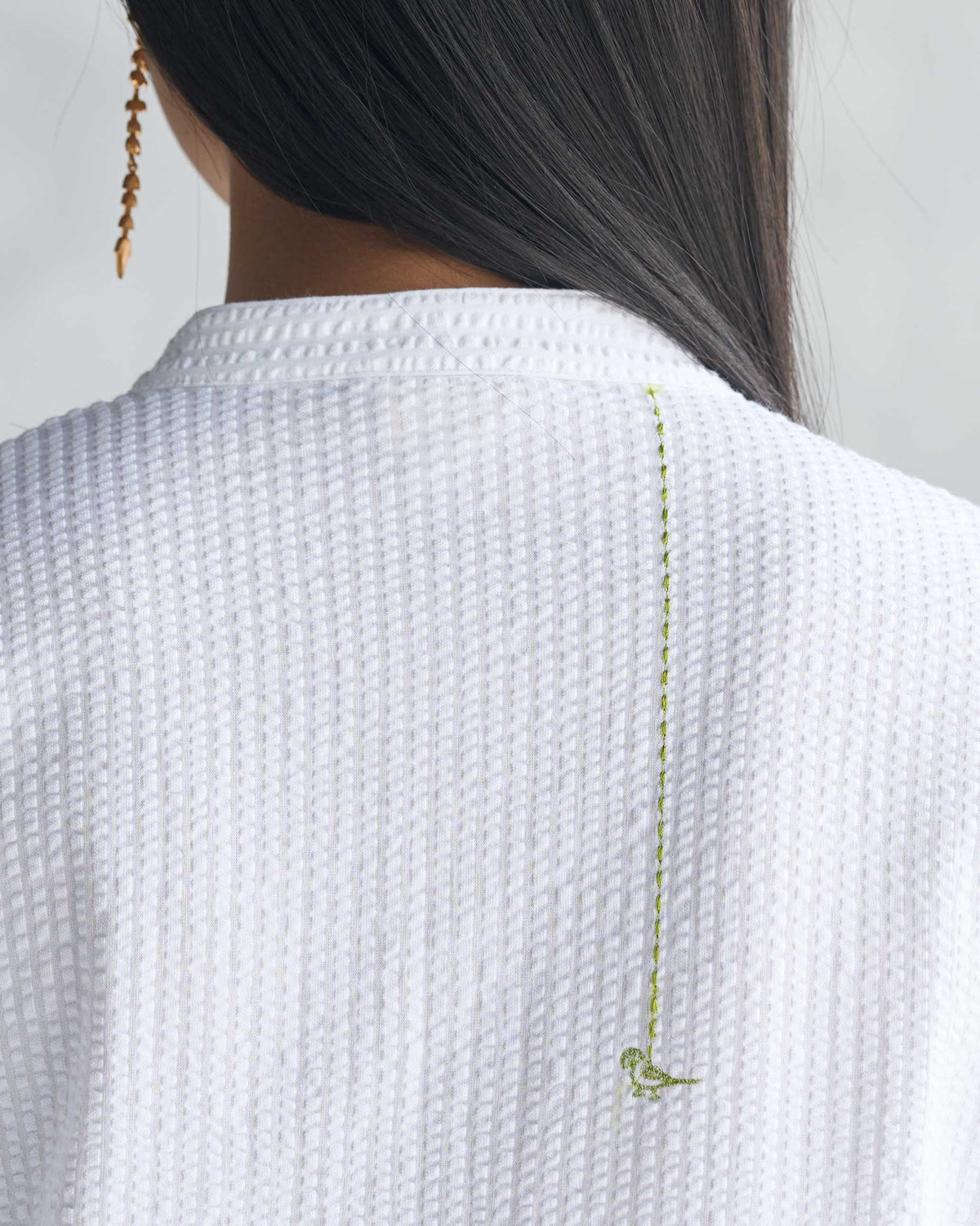 Close-up of lime green bird embroidery on a white seersucker long kurta.