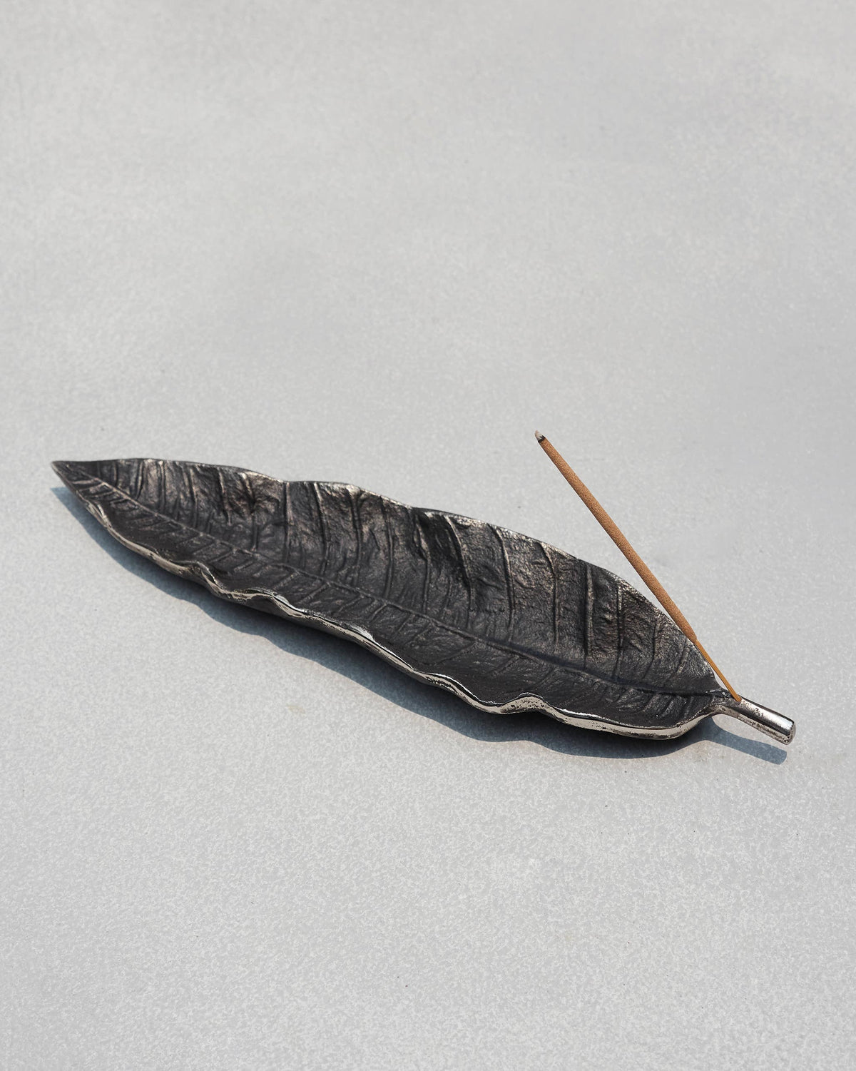 Mango leaf Incense Holder with an incense stick laid across it at an angle.