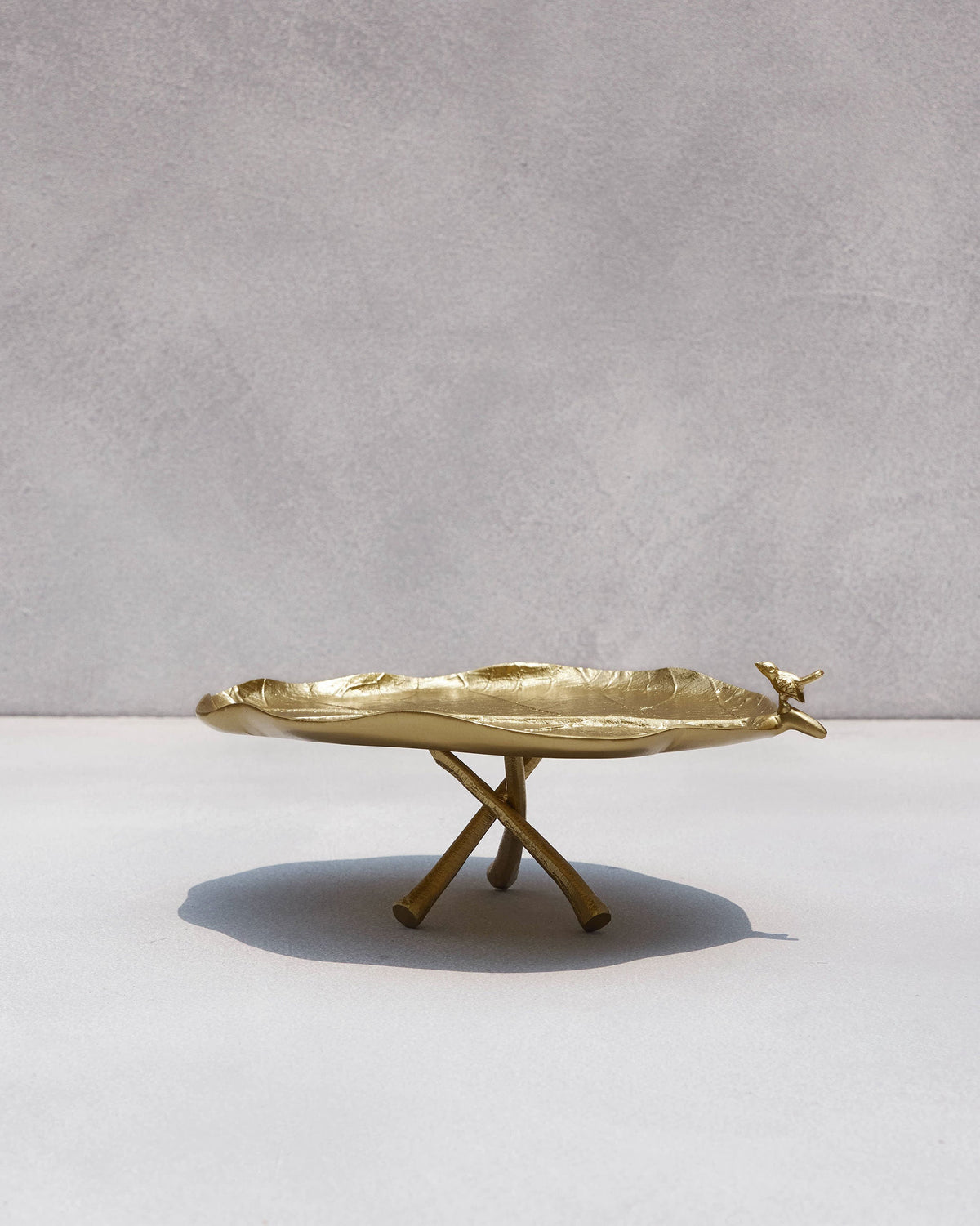 Side view of a Leaf Deco Tray on crossed legs, with a small bird at the edge.