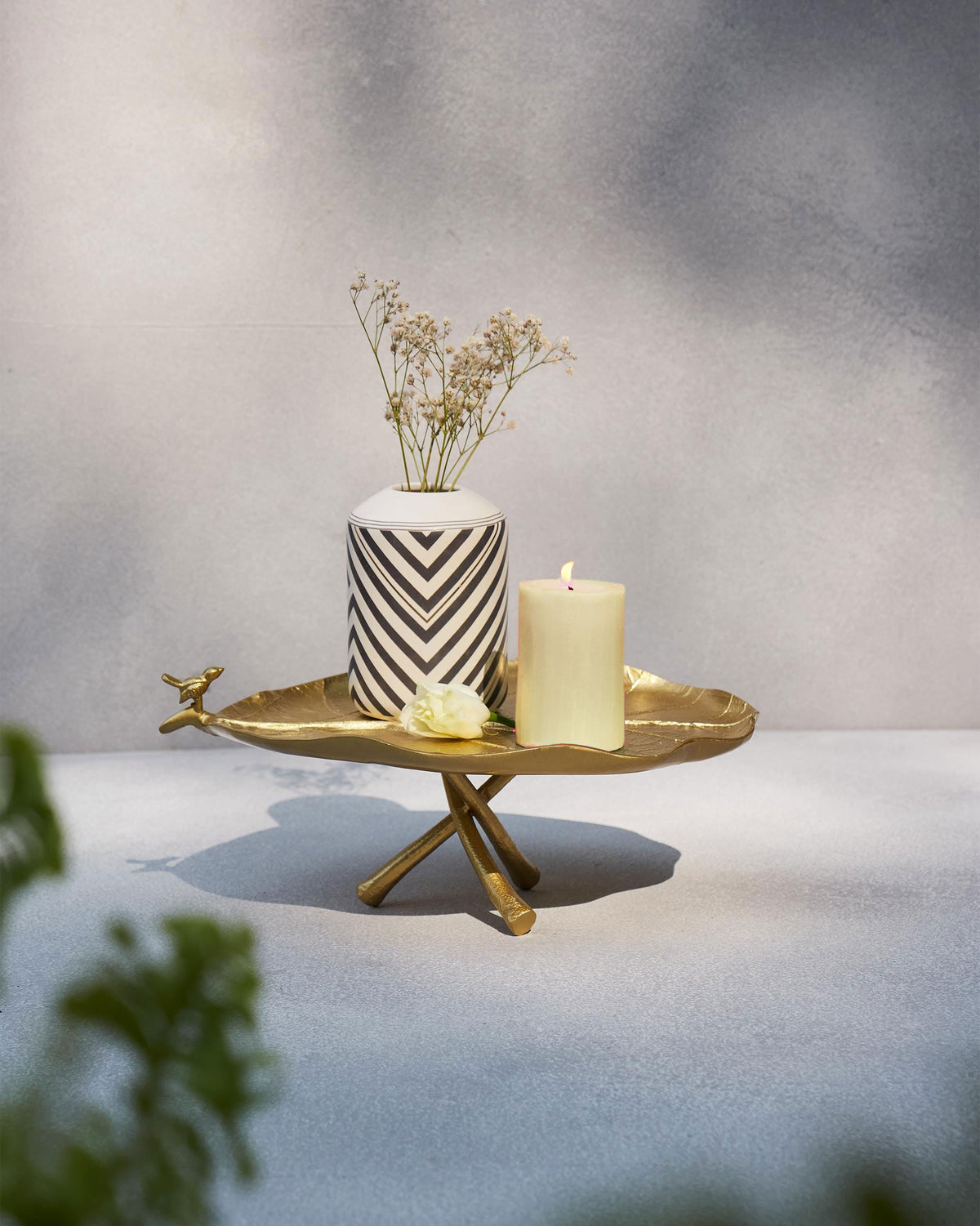 Leaf Deco Tray holding a candle, a striped vase and a small flower.