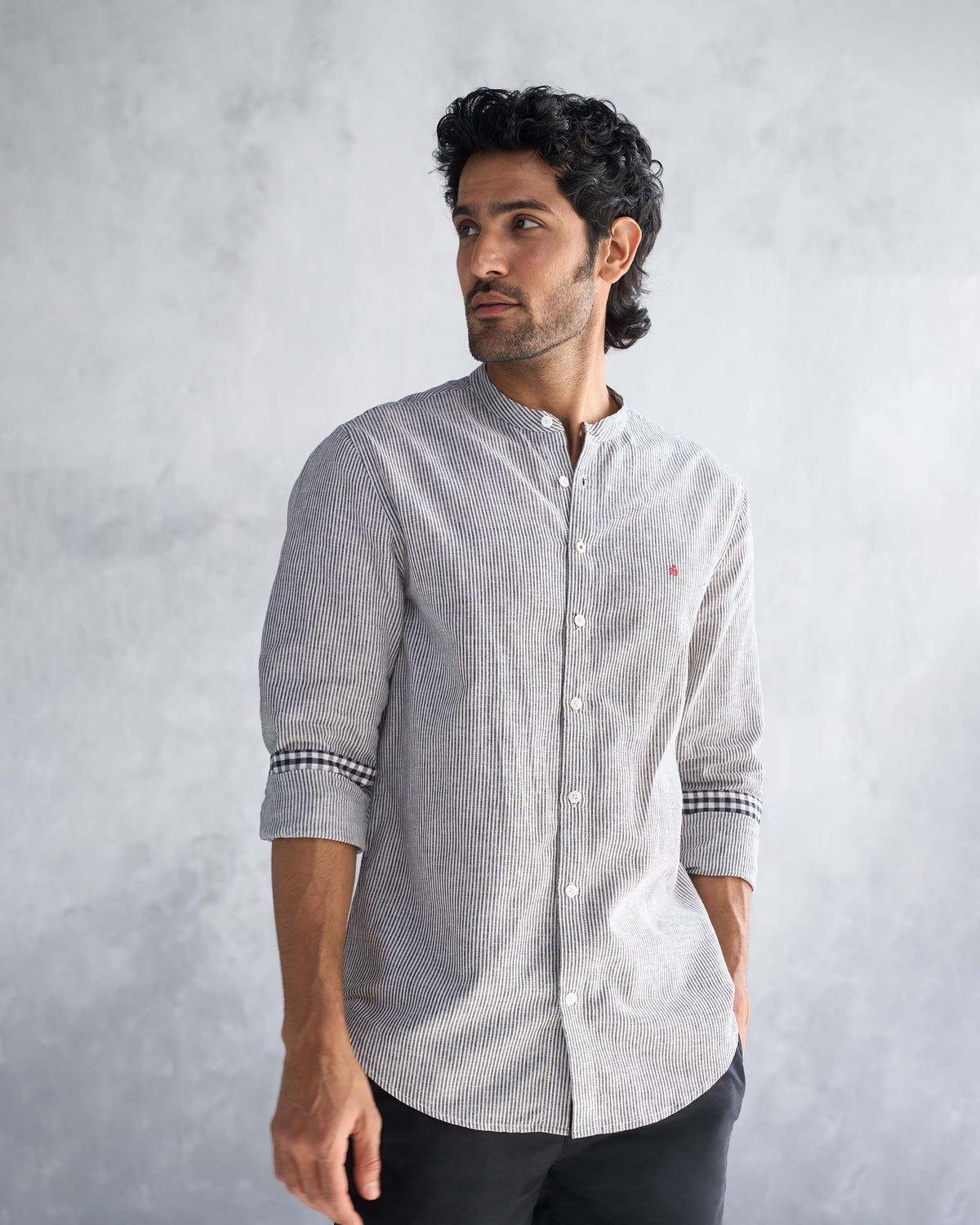 Person wearing a charcoal stripe Nawab shirt with a checked cuff.