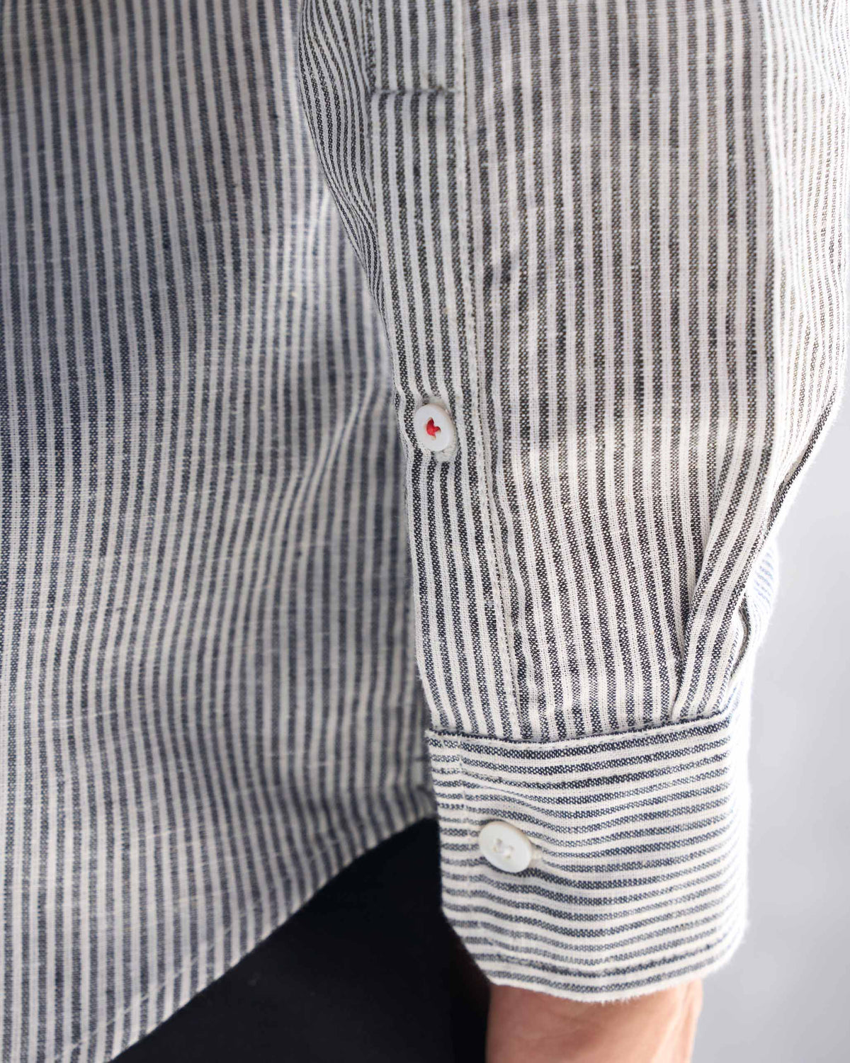 Close-up of a charcoal stripe Nawab shirt showing a sleeve button and cuff.