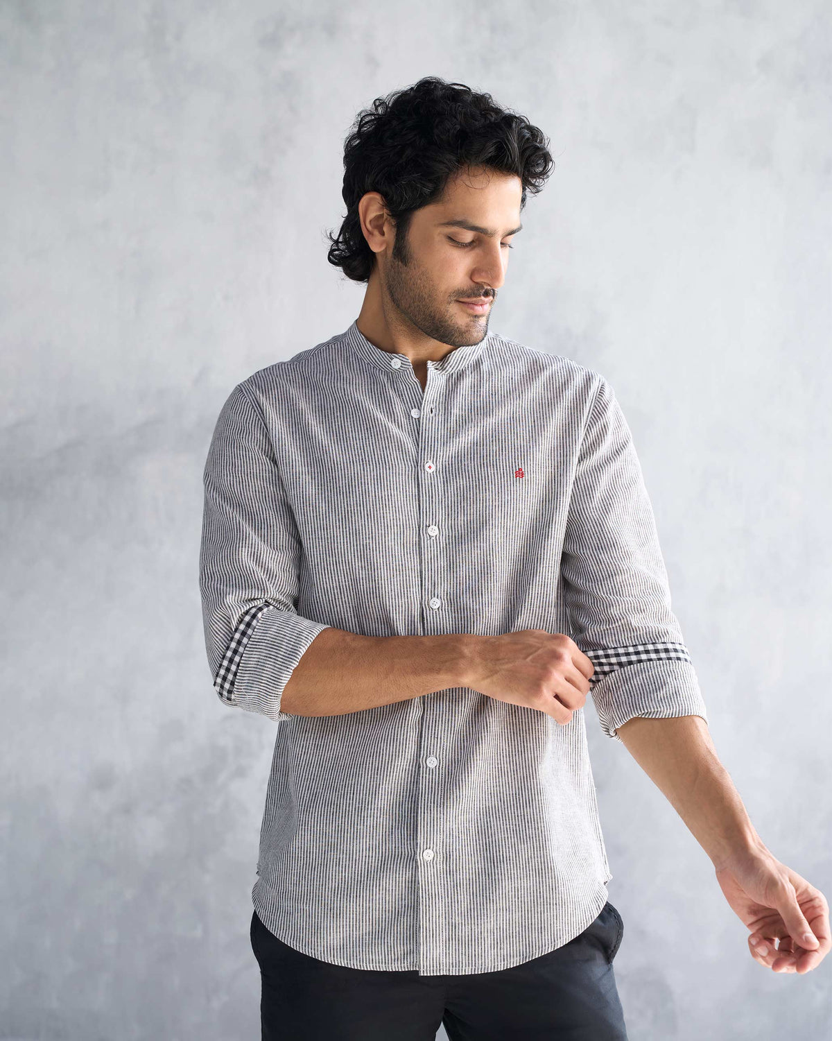 Person wearing a charcoal stripe Nawab shirt with a checked cuff.