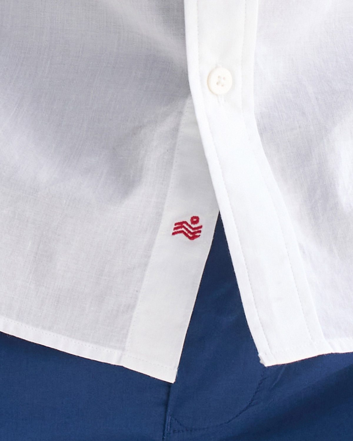 Close-up of a red logo embroidered inside the placket of a white Classic shirt.