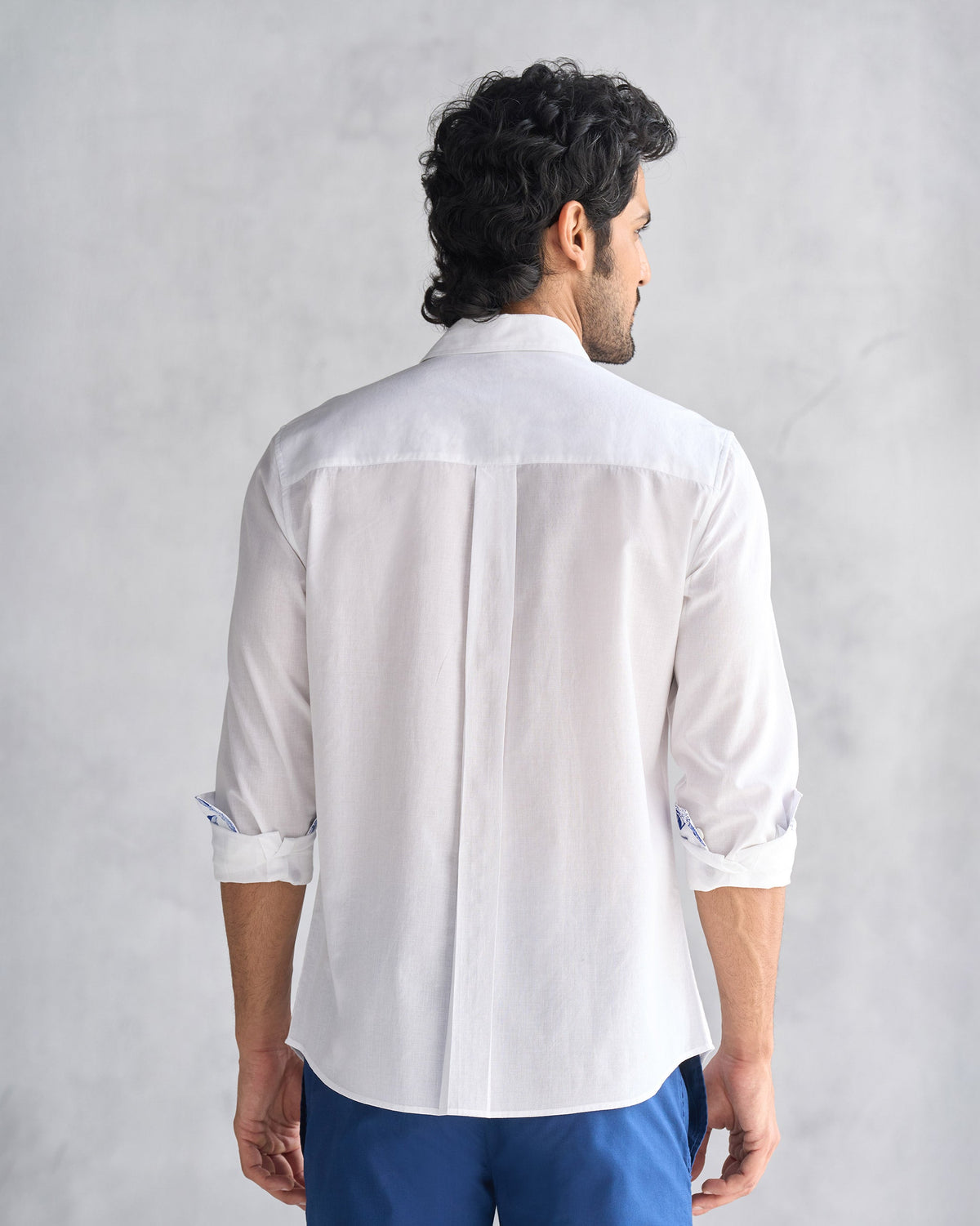 Back of a white Classic shirt with a box pleat and blue cuff lining.