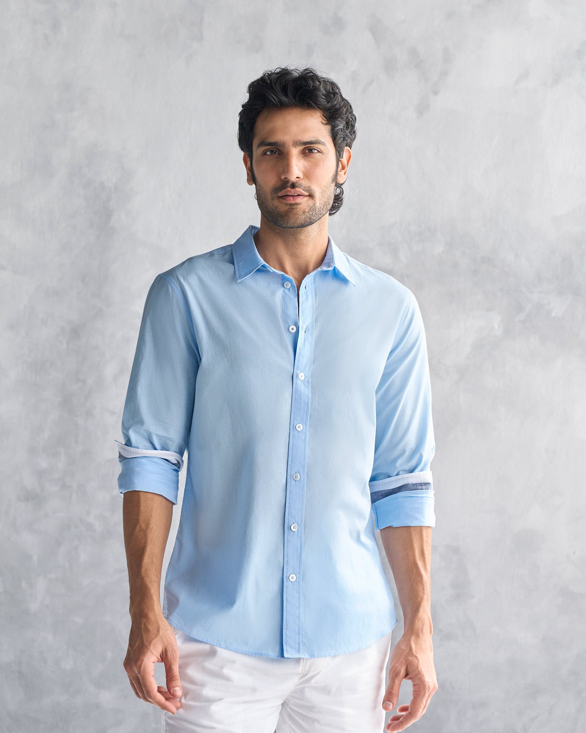 Person wearing a light blue classic shirt with rolled sleeves.