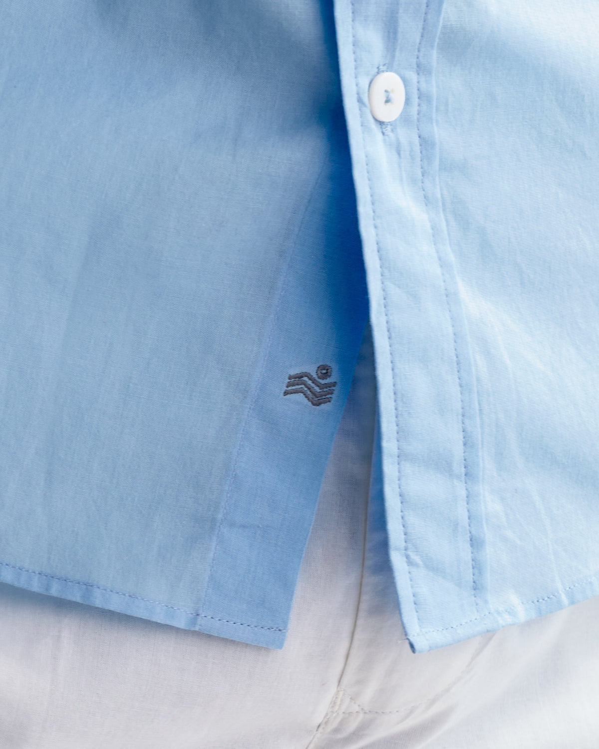 Light blue classic shirt with a small wave logo at the hem.