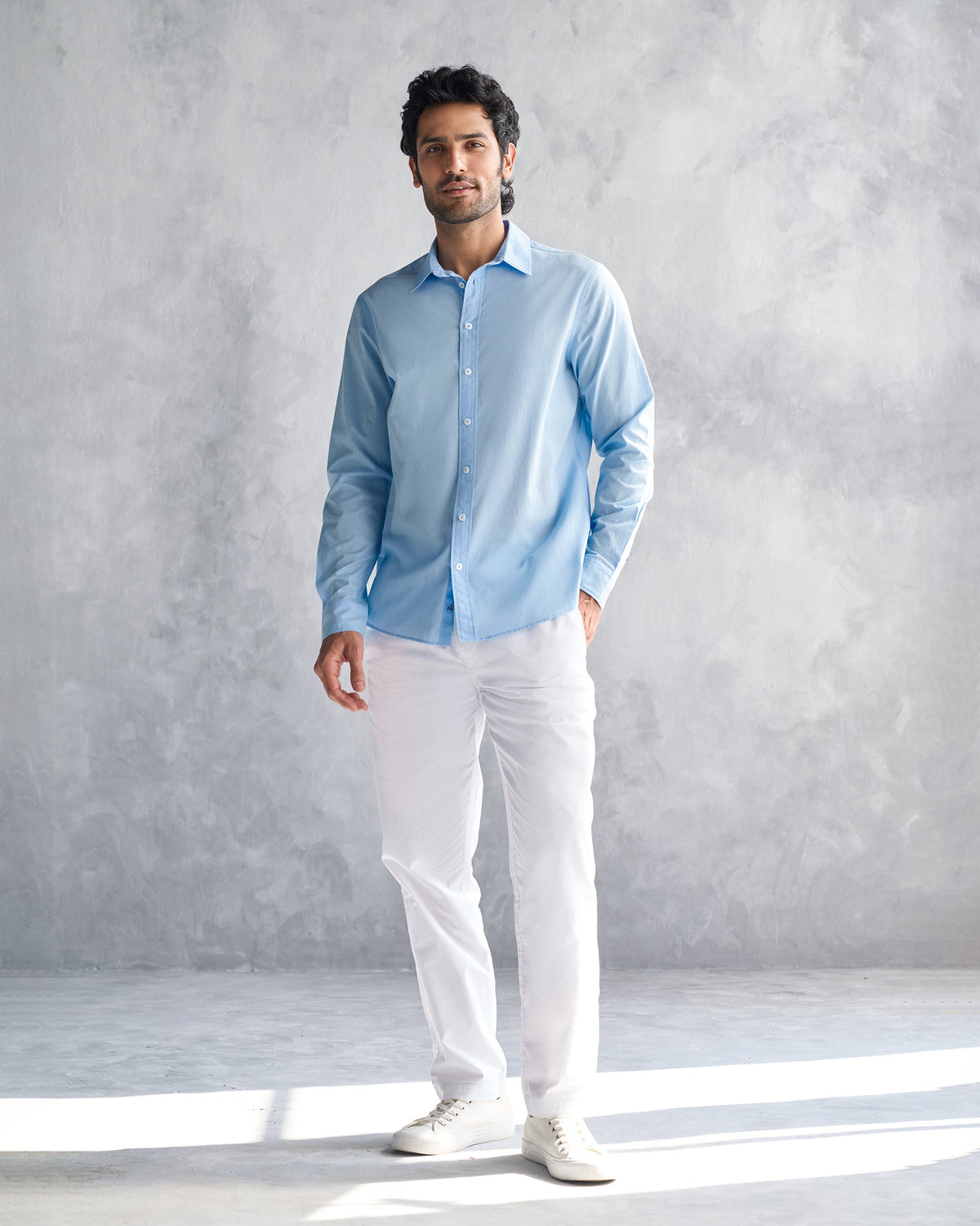 Person wearing a light blue classic shirt untucked.