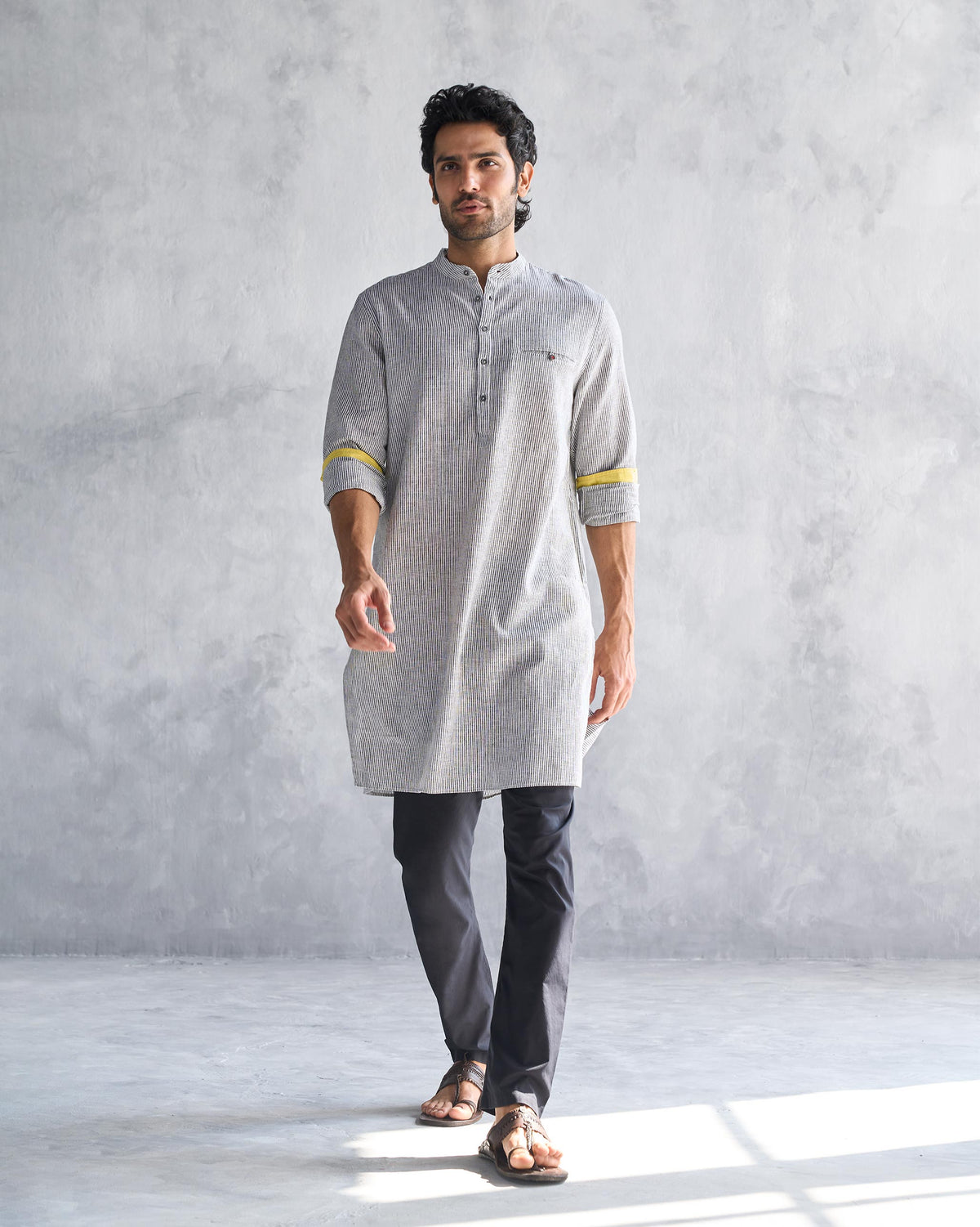 Person wearing the Pondicherry Kurta in charcoal stripe with yellow cuff lining.